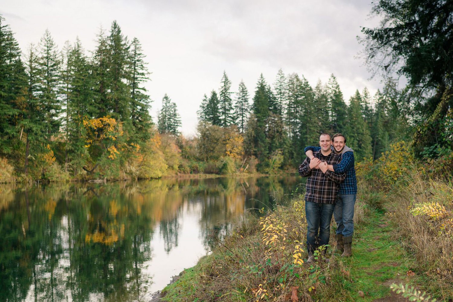 Same-sex couple engagement photos on an Oregon forest path with autumn greenery and fall colors.