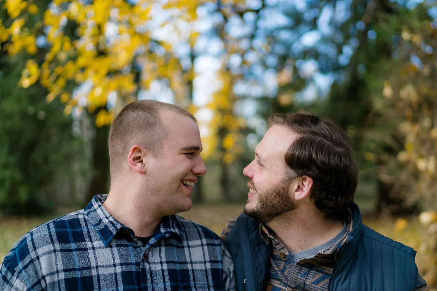 Same-sex couple engagement photos in an Oregon forest with golden autumn leaves in the background.