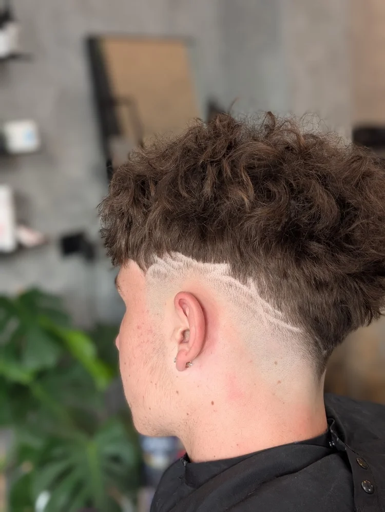 Curly fade with hard part design line cut into the side