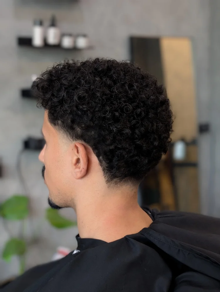 Barber buzzing a client's hair in front of the Bsharp signage