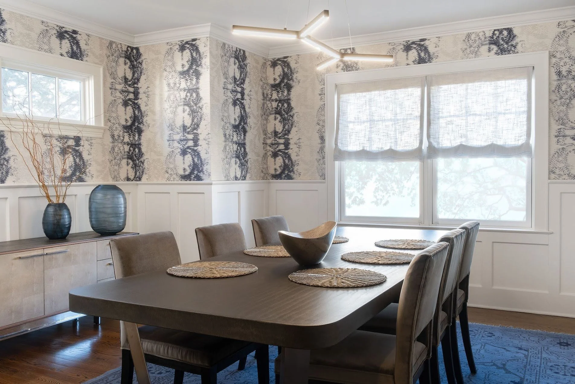 Modern dining room in a Larchmont Colonial featuring custom wallcovering, contemporary lighting, upholstered dining chairs, and custom millwork.