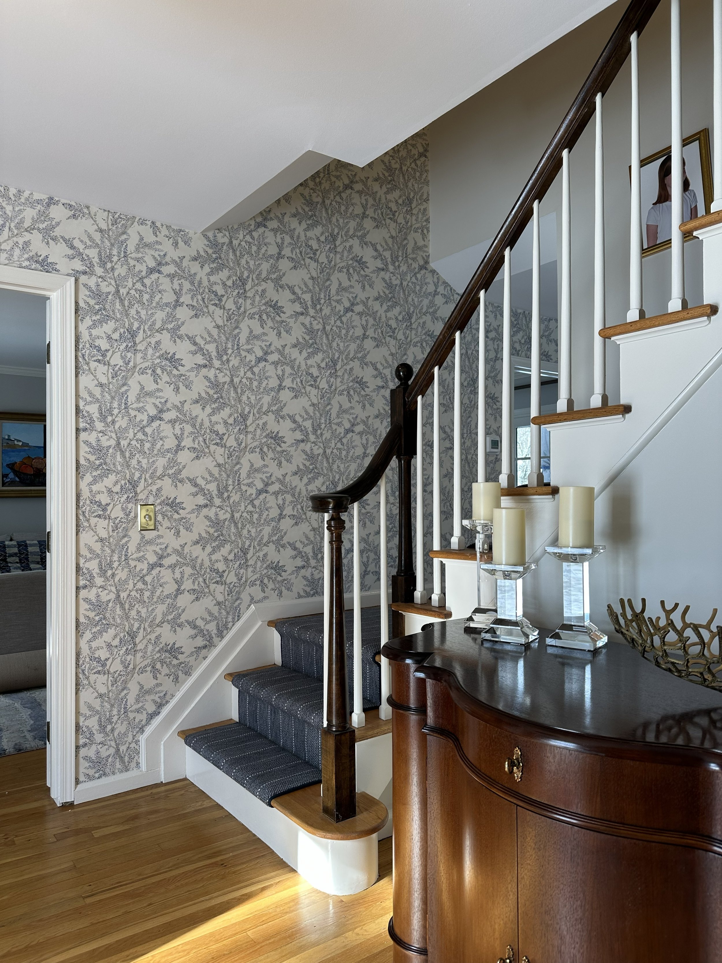 Sanderson wallpaper, navy stair runner, and mahogany entry chest in Irvington NY home