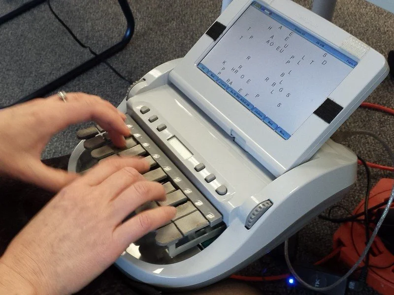 A court reporter actively working, typing on a stenograph keyboard during a legal proceeding for real-time transcription.**
