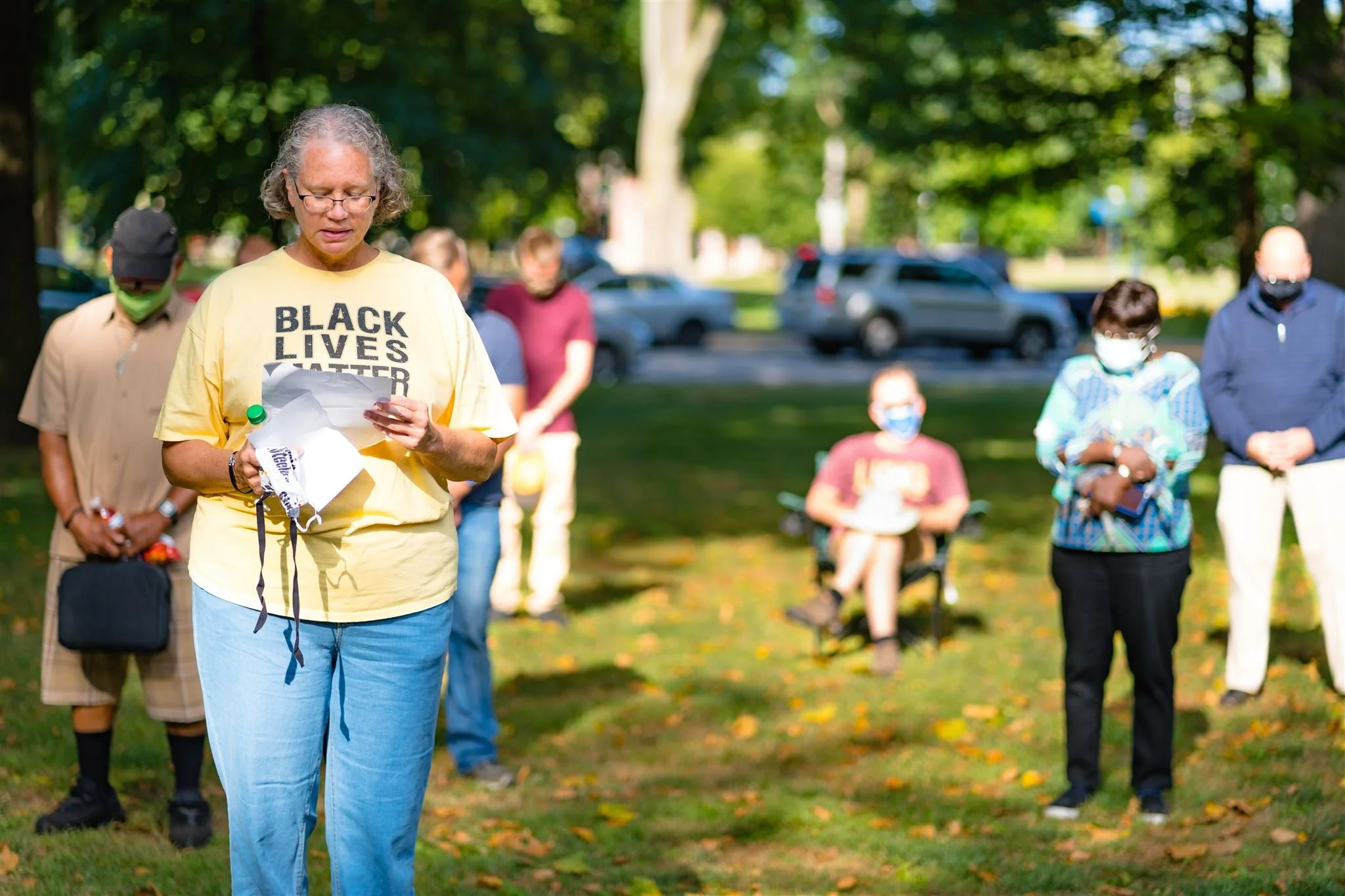 A woman in a yellow shirt that says "Black Lives Matter" prays during a vigil in Beaver, PA.