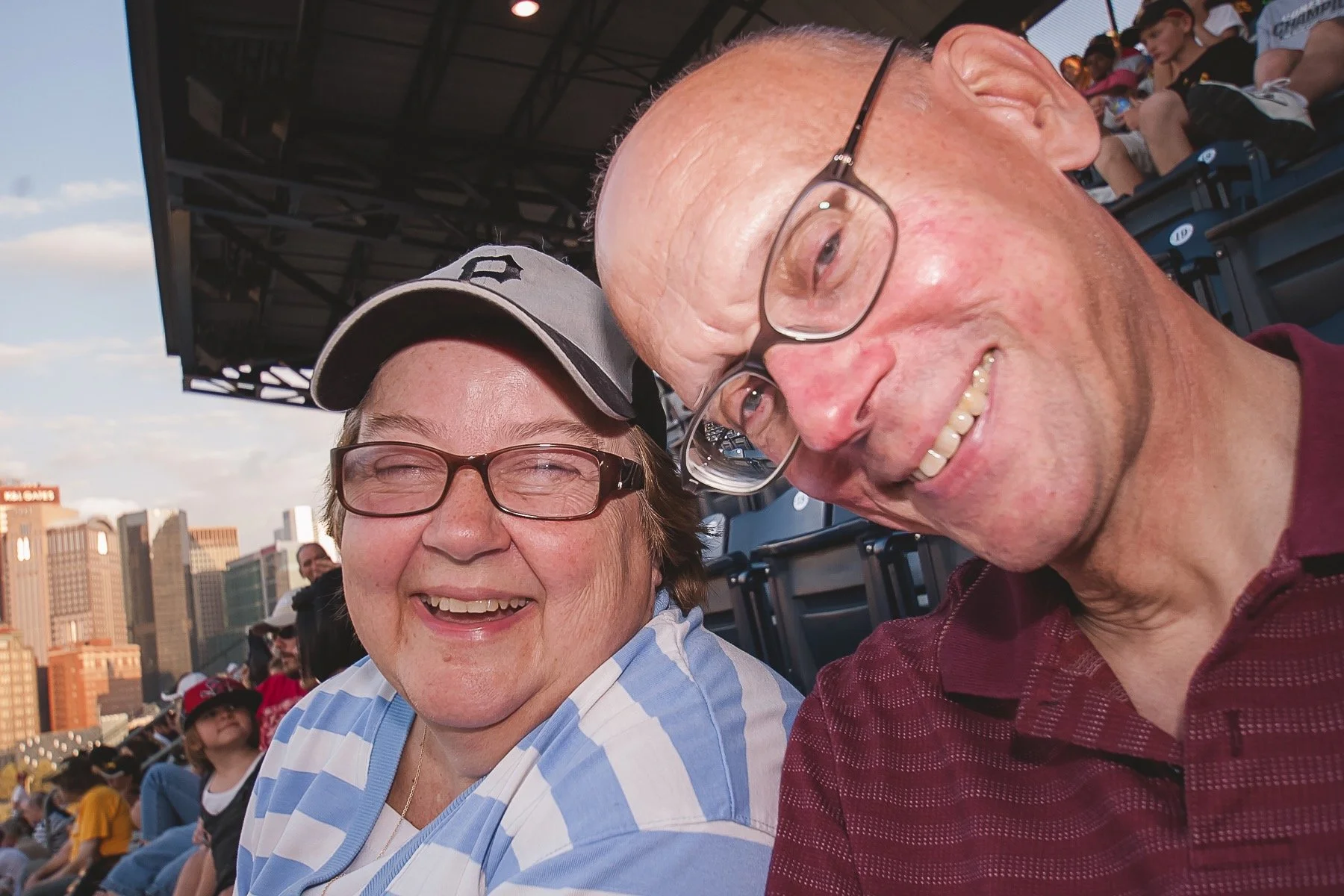Husband and wife smile from the cheap seats at PNC Park during a Pittsburgh Pirates home game.