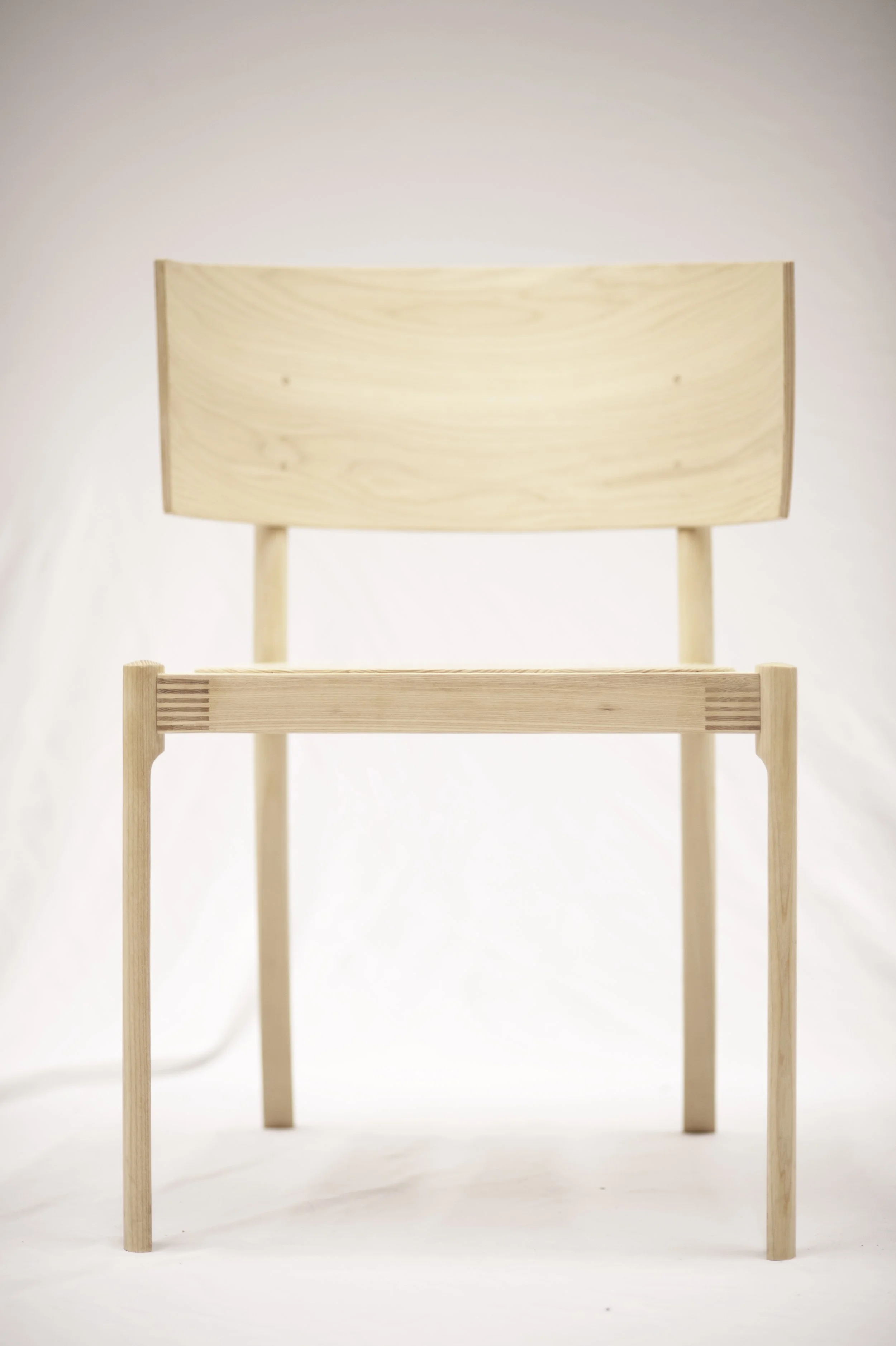 A wooden chair with a high curved back, set against a plain white background.