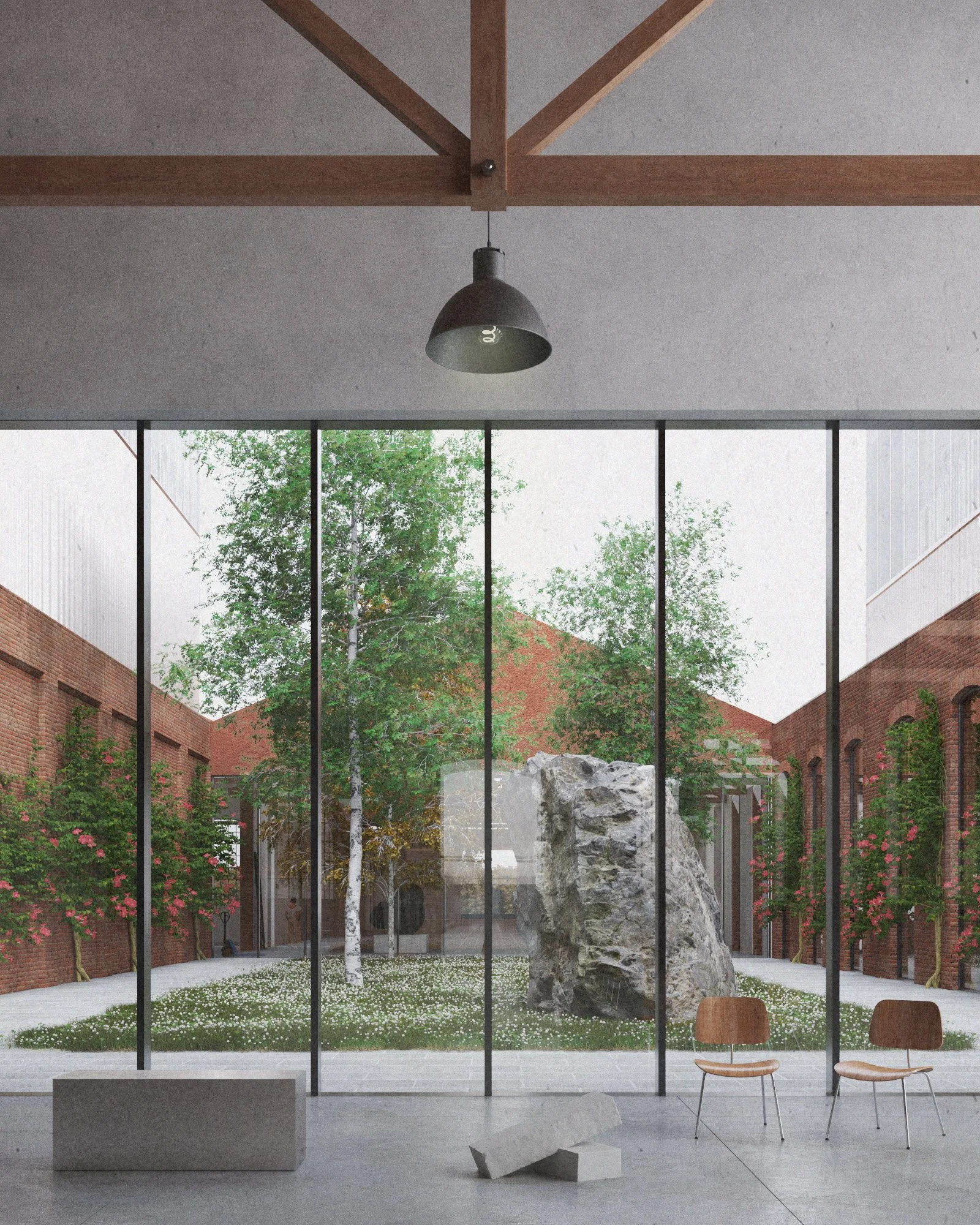Modern interior space with large floor-to-ceiling windows overlooking a courtyard with trees, large rocks, and brick buildings. Inside, minimalist furniture including a rectangular white bench and two wooden chairs are visible.