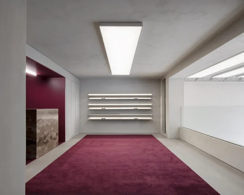 Minimalist interior with white walls and ceiling, purple carpet, and wall-mounted shelves with lights.