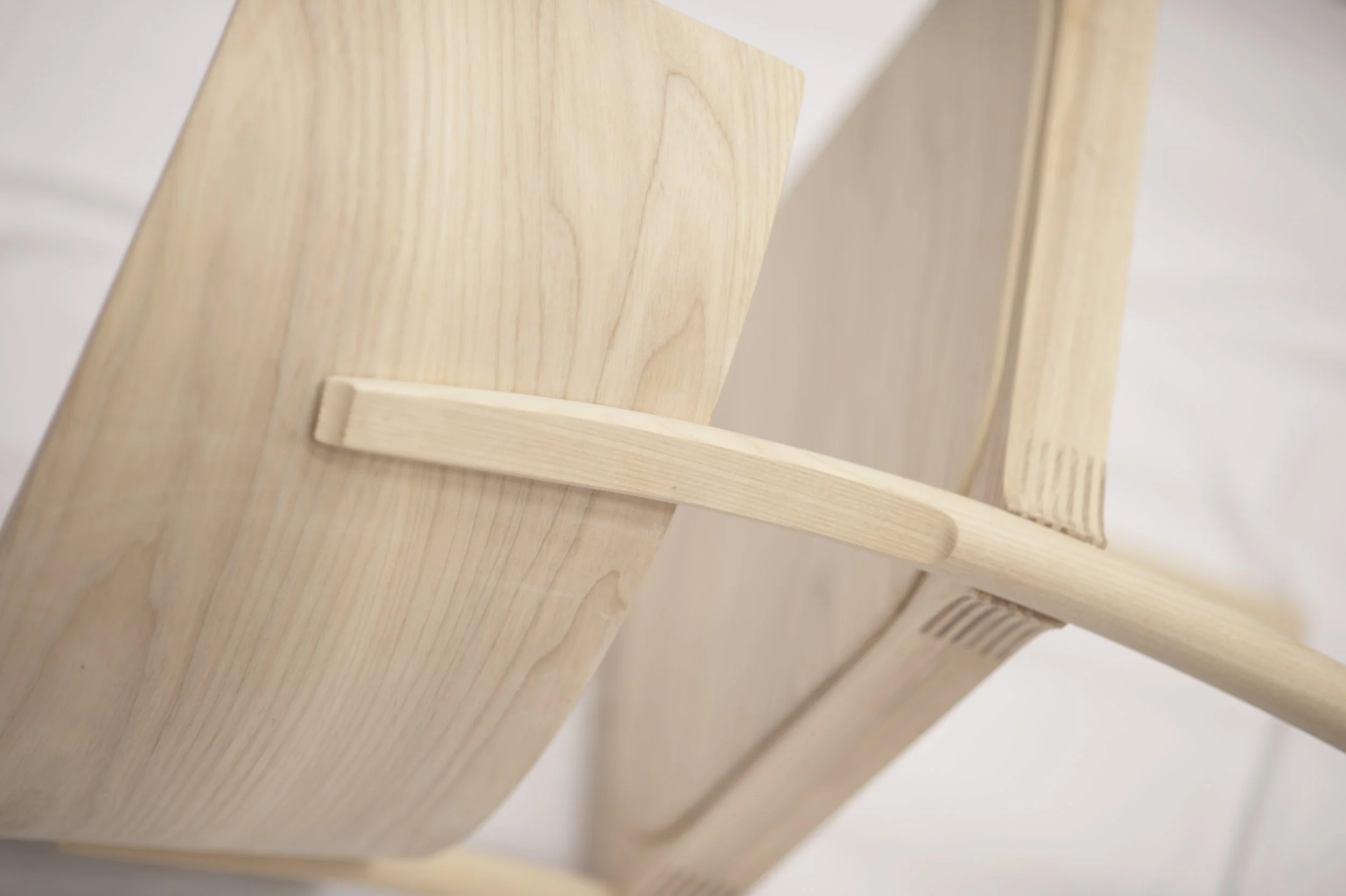 Close-up of a wooden bookshelf with a light natural finish, showing smooth grain and a small ledge, against a neutral background.
