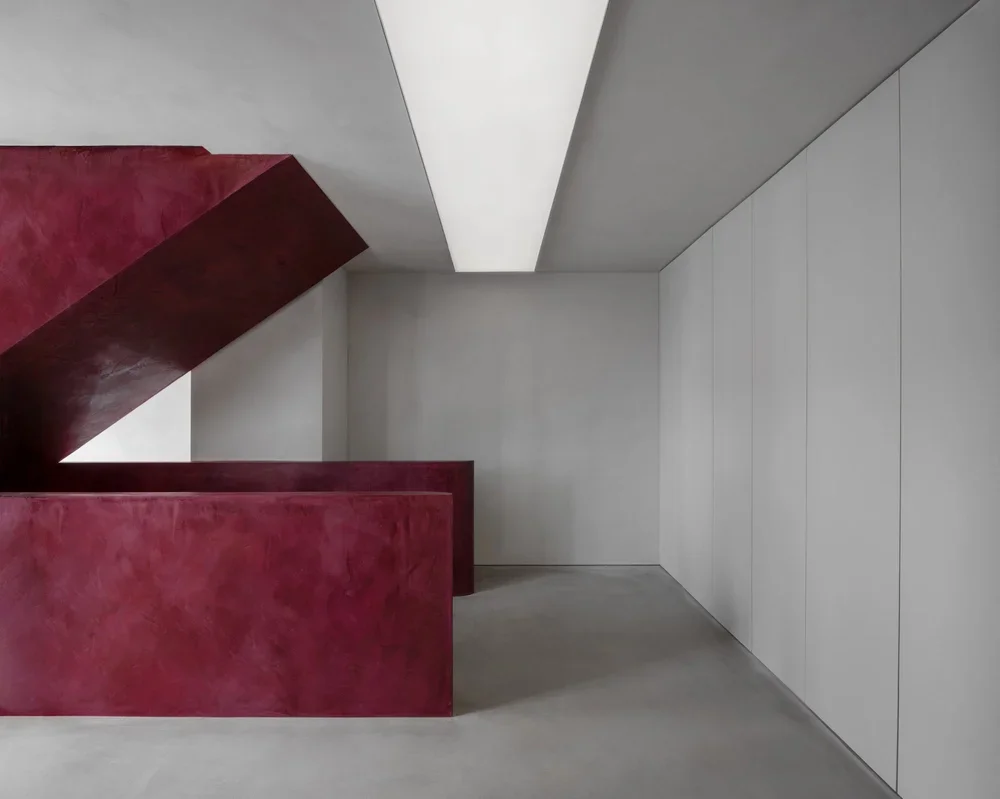 Minimalist interior with a red staircase and white walls and ceiling.