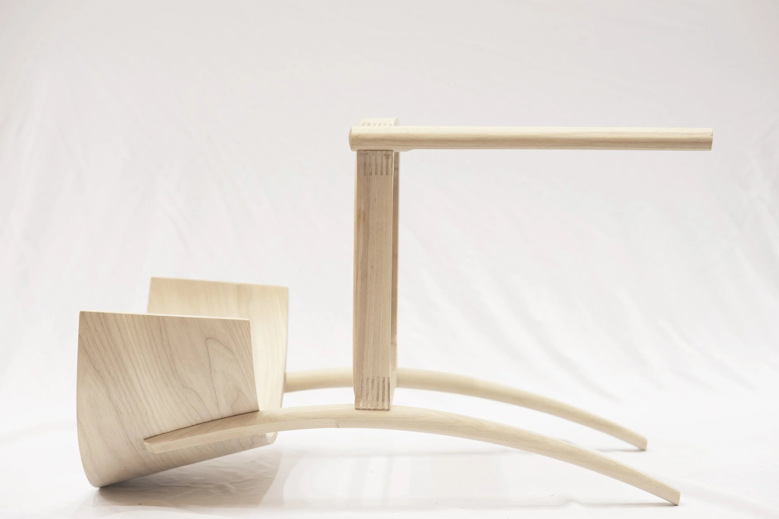 Minimalist wooden chair with a curved backrest, vertical support structures, and an elegant design, set against a plain white background.