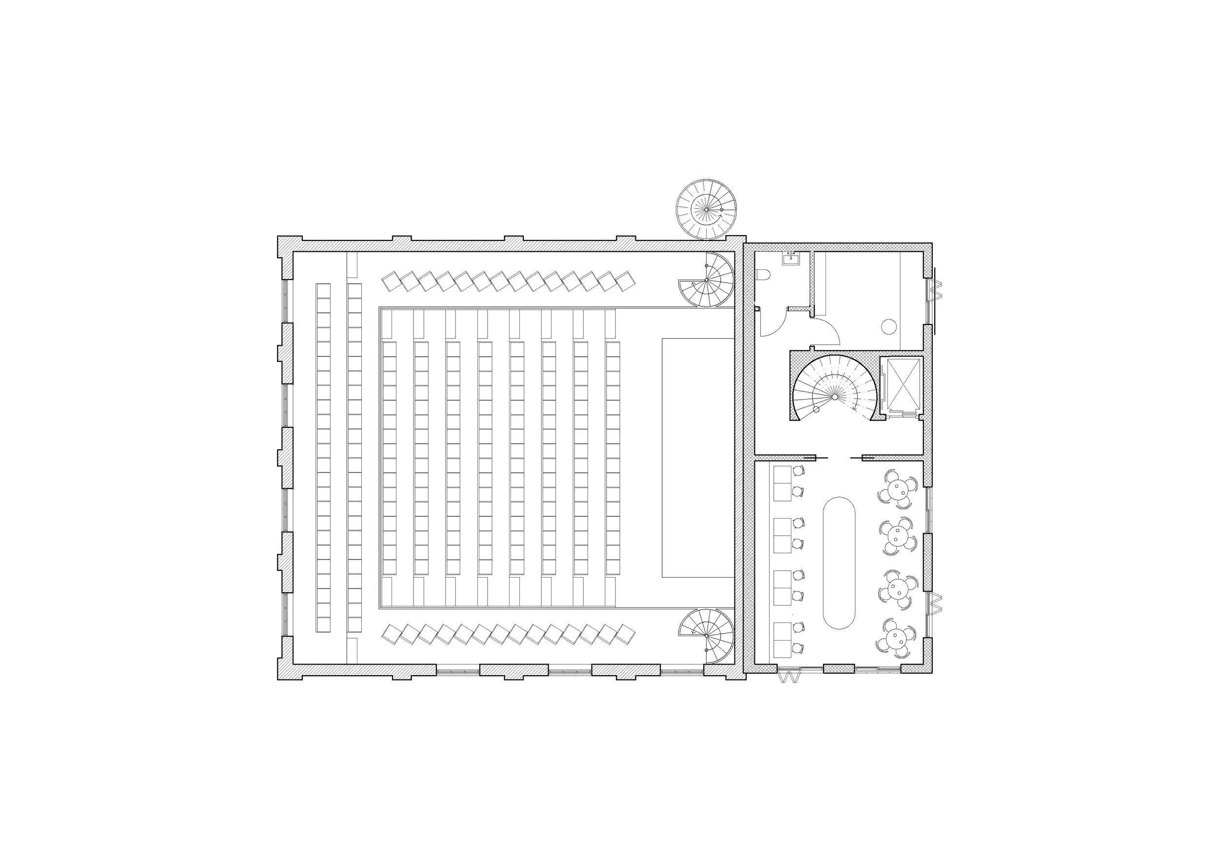 Floor plan of a building's interior, showing a large room with multiple rows of seating, a spiral staircase, a small enclosed bathroom, and a lounge area with tables and chairs.