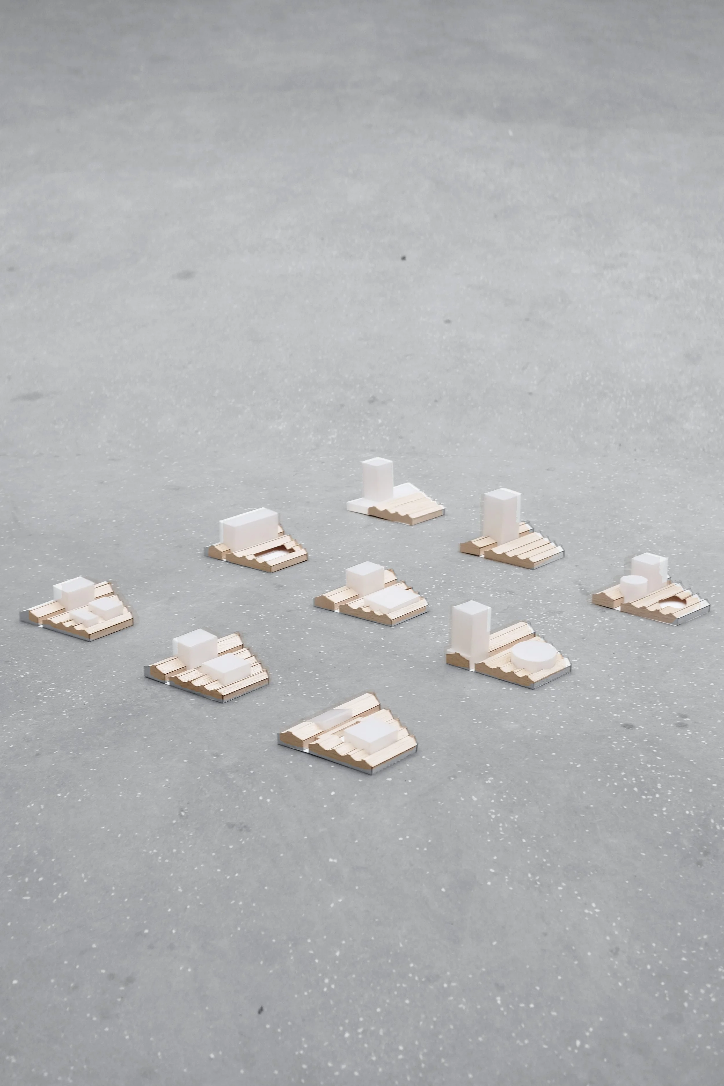 Architectural models of buildings arranged on a flat, gray surface.