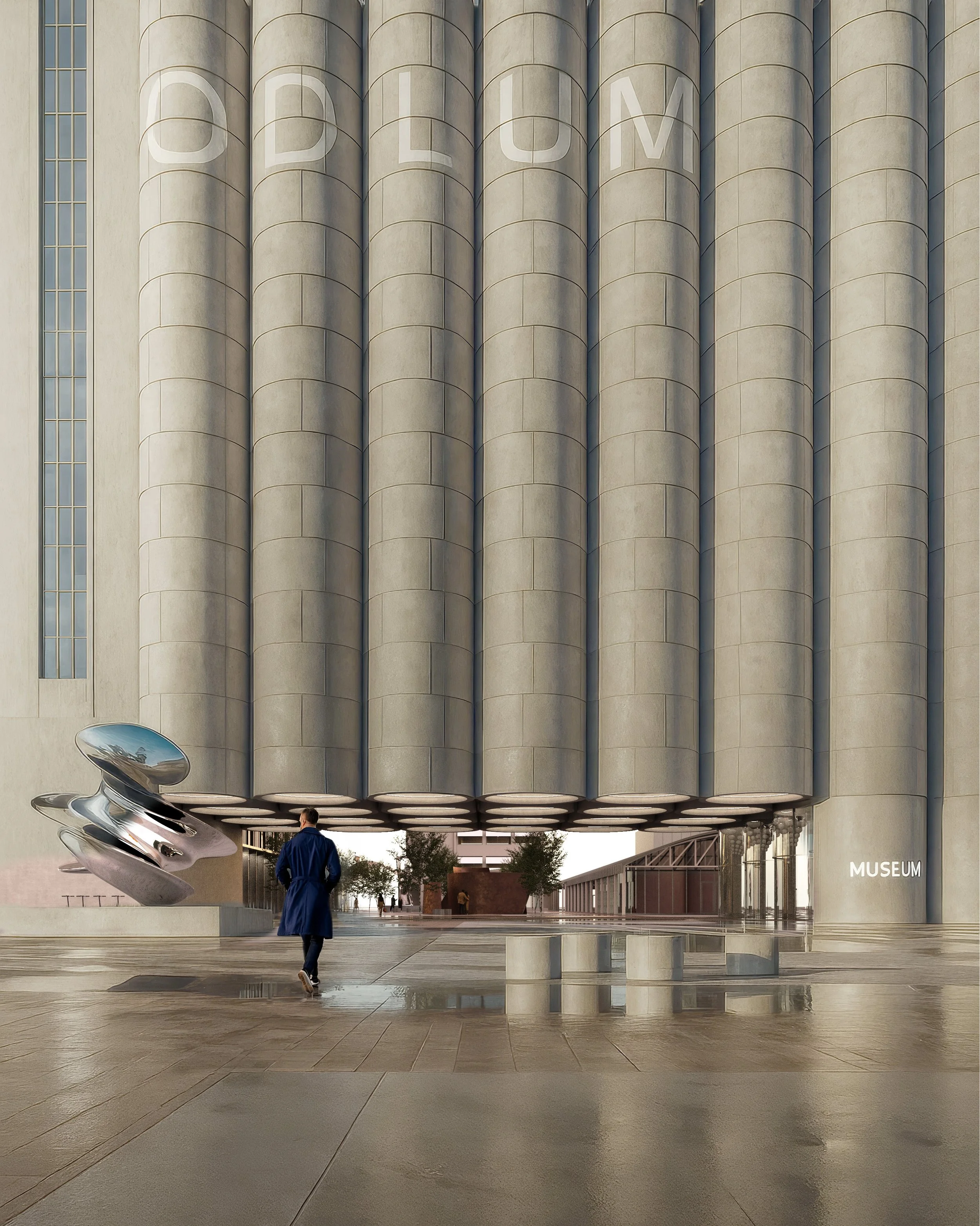 Modern museum entrance with large cylindrical architectural elements, a metallic sculpture on the left, and a person walking, with trees and a pathway in the background.