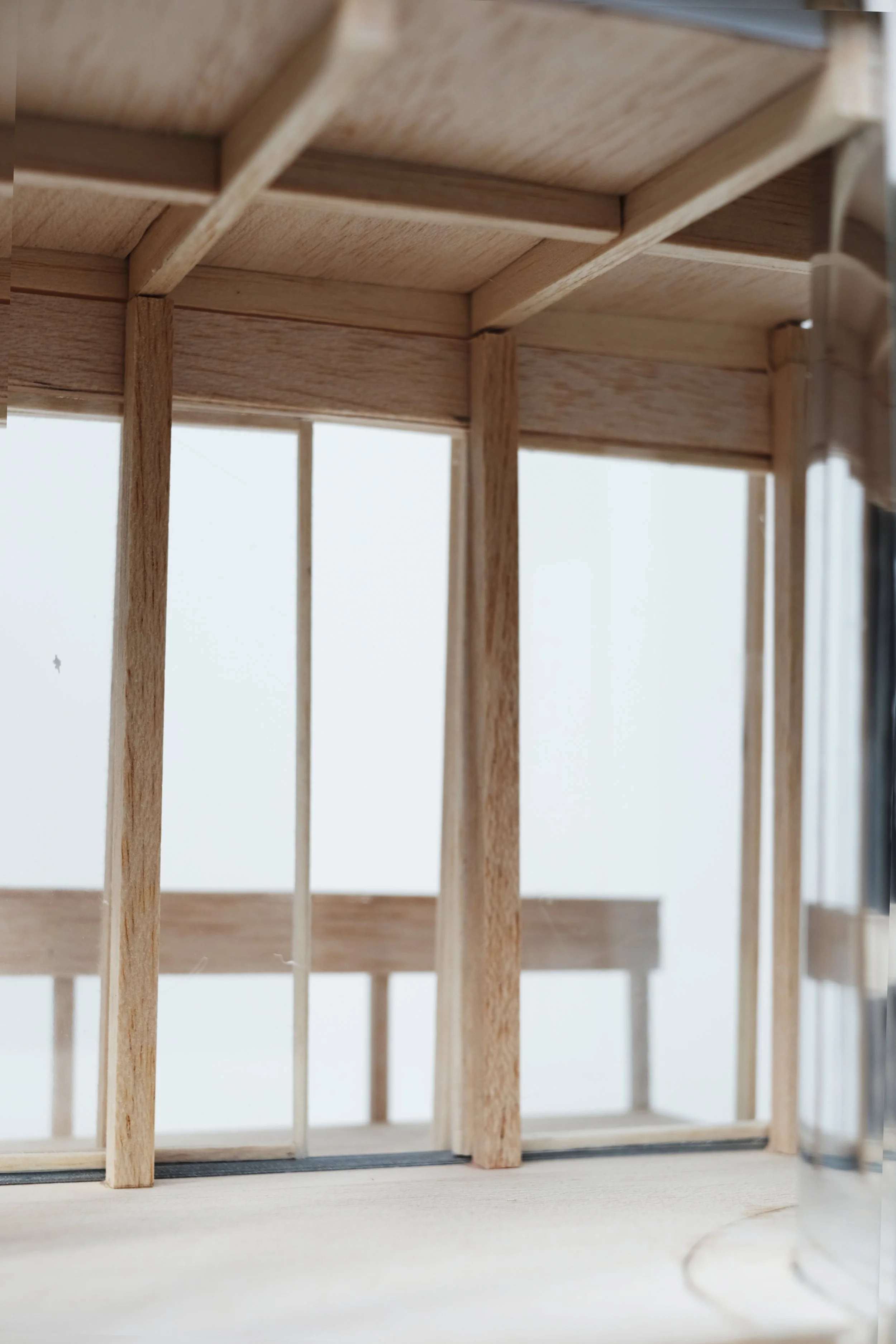 Close-up of a small wooden structure, possibly a dollhouse or model building, with vertical and horizontal wooden sticks creating a frame.