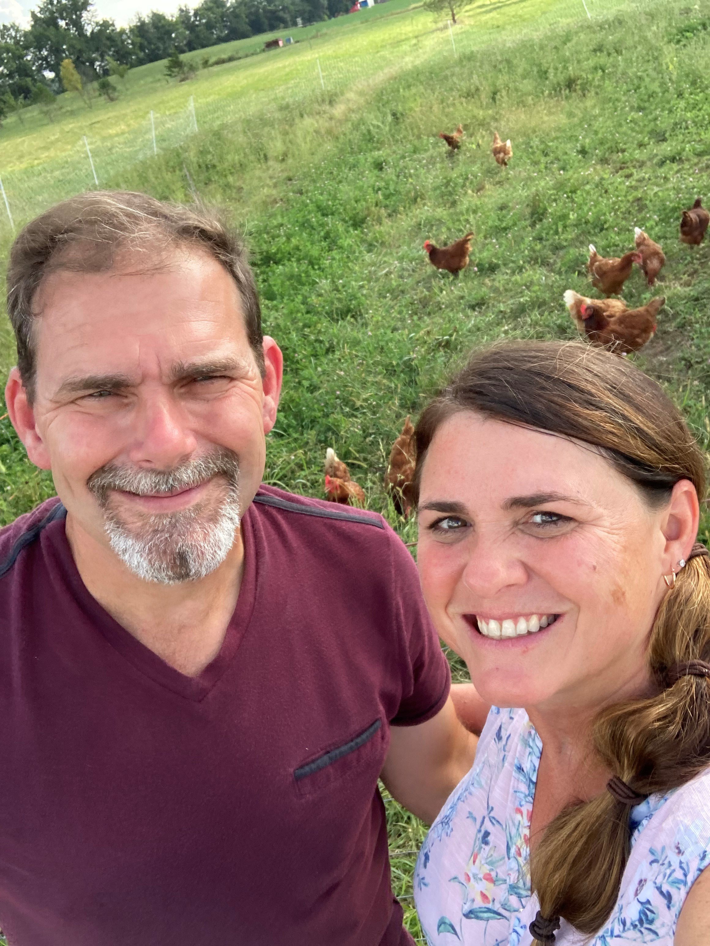 Russell and Amanda at home on the farm with some chickens in the background.