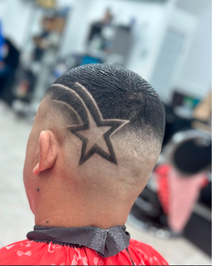 Close-up of a person's freshly shaved hairstyle featuring a star and lightning bolts design shaved into the side of the head.