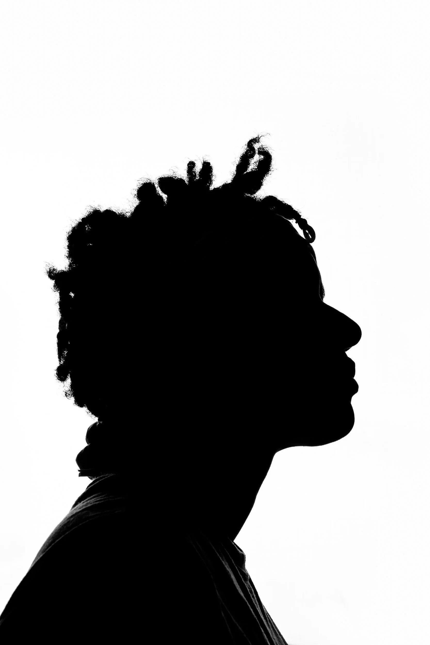 Silhouette of a person with curly hair and glasses in profile against a white background.