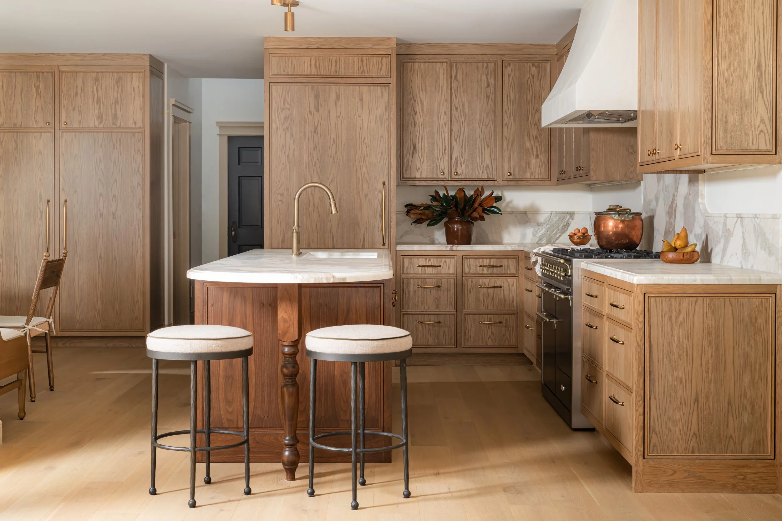 Interior of a house under construction with hexagonal beige floor tiles, unfinished cabinetry, and walls with electrical outlets and exposed wiring.