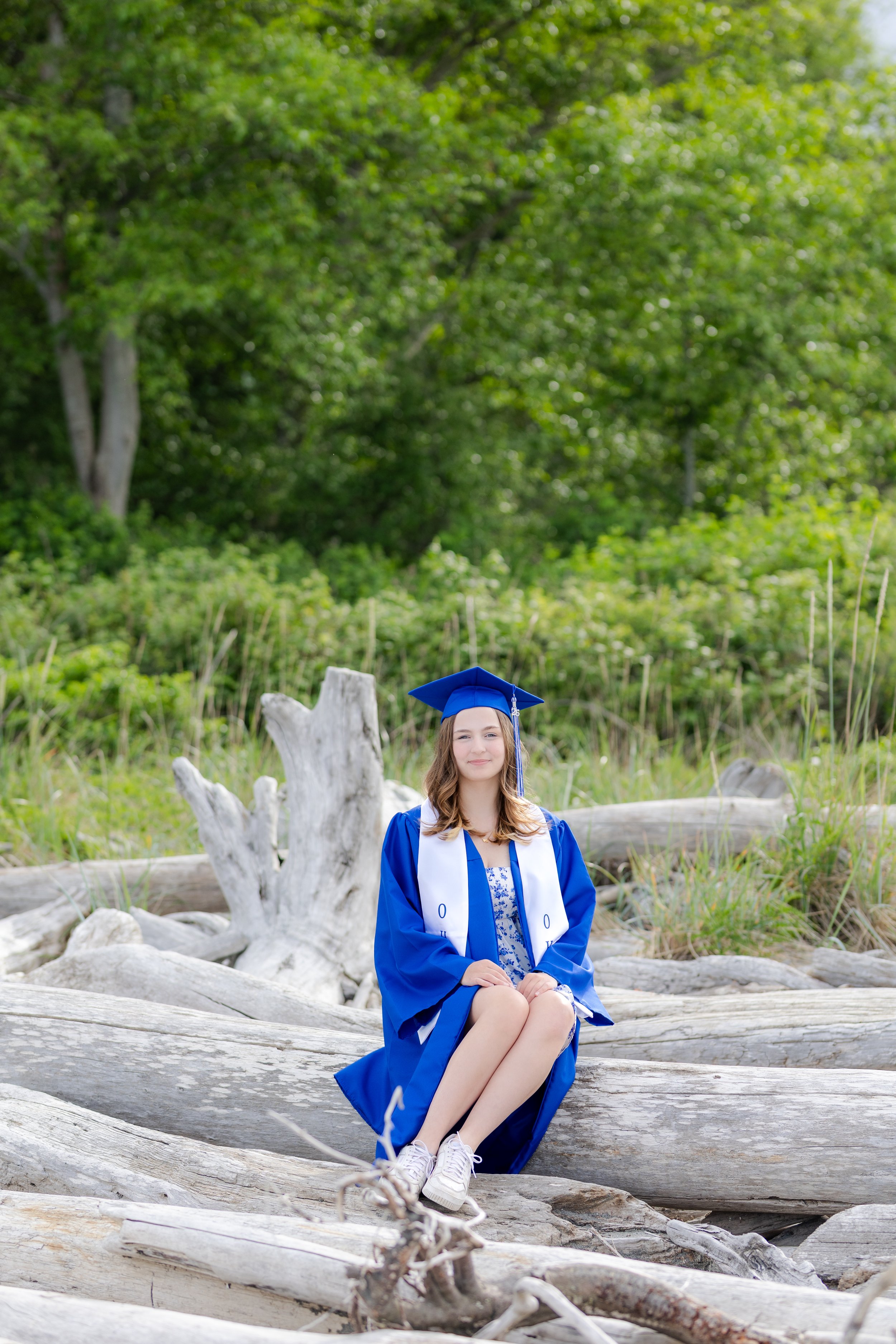 Kitsap cap and gown graduation picture at the beach sitting on driftwood