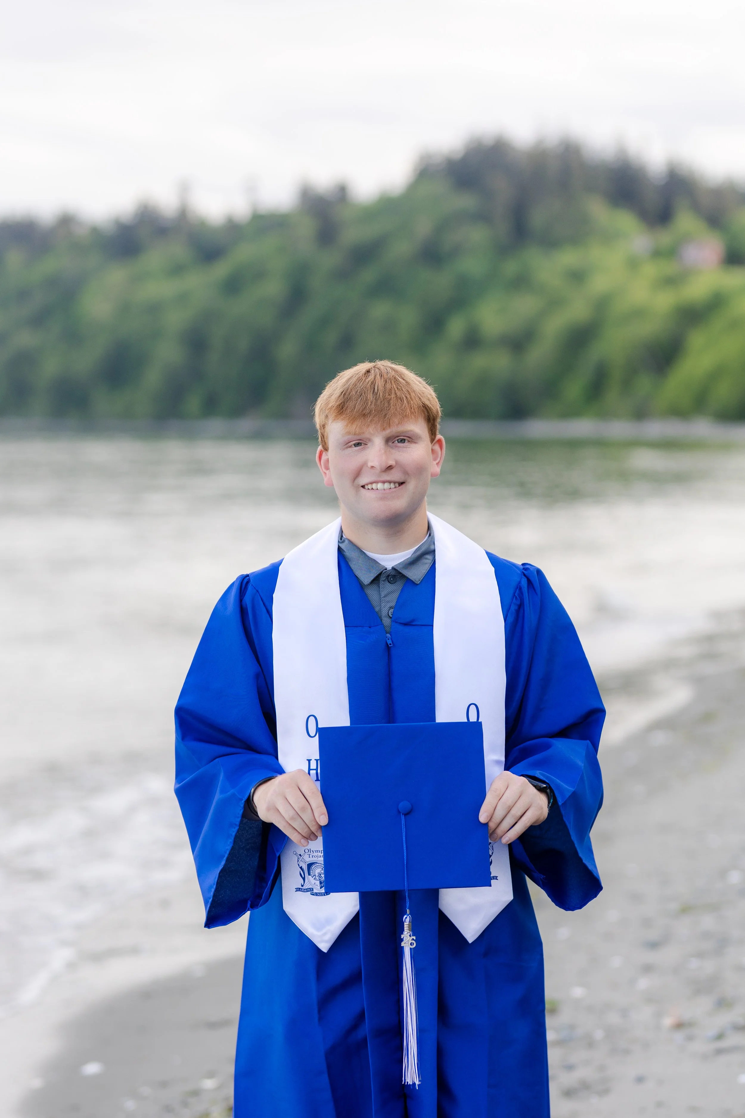 Olympic High School graduation picture of senior in cap and gown on the beach