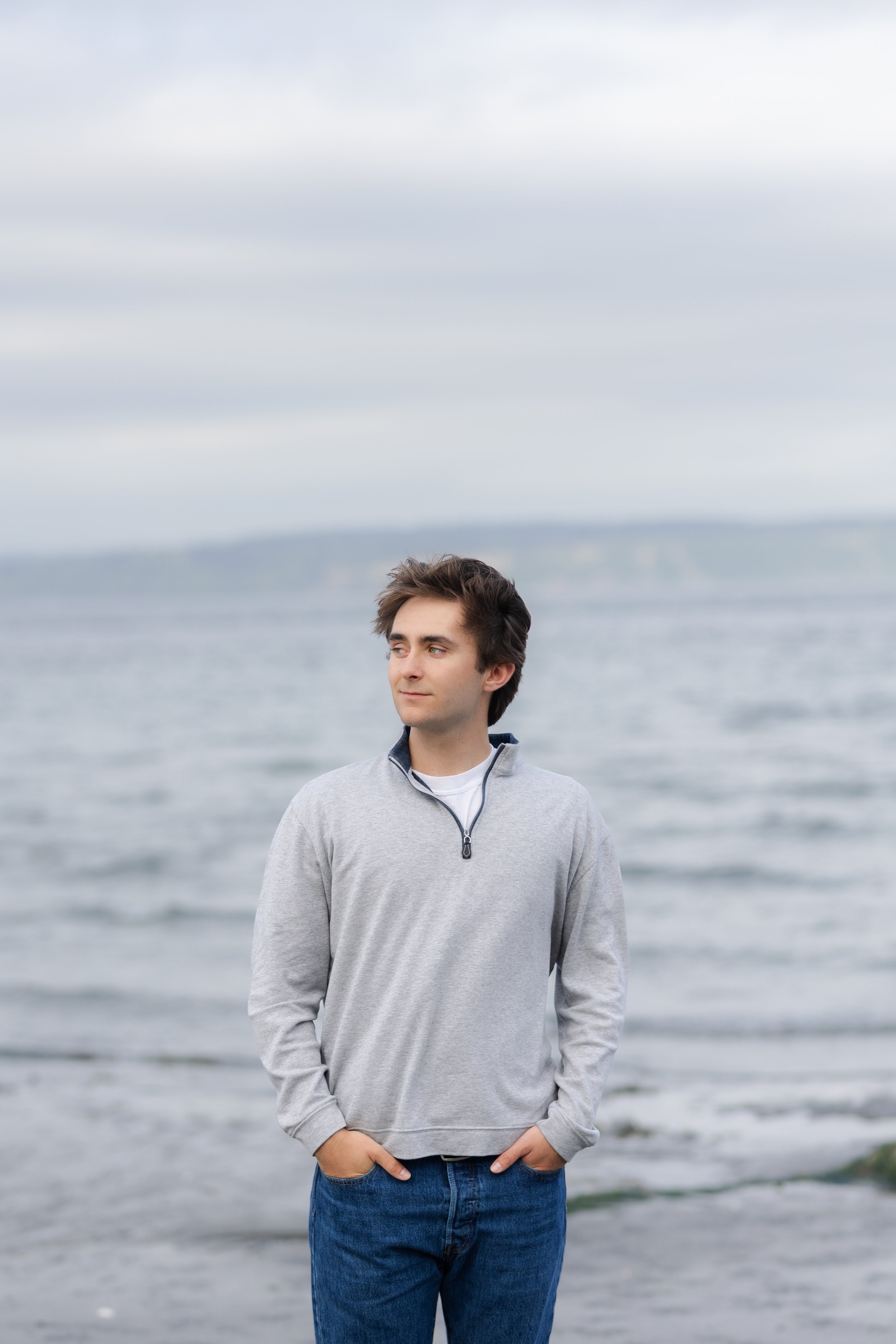 Senior picture taken on a cloudy Washington day with grey water and grey skies at the beach