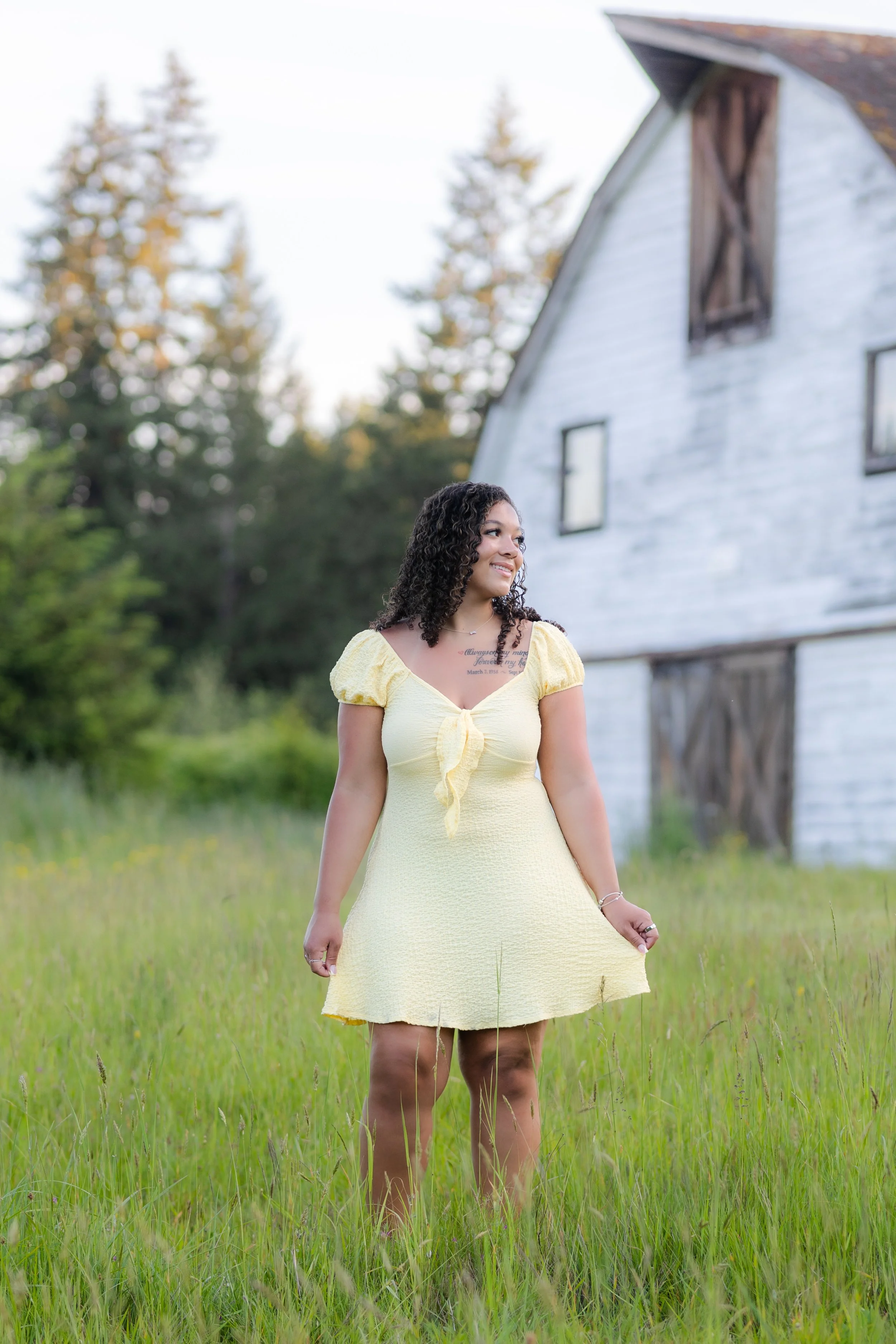 Senior picture in Port Orchard, WA of a girl in a yellow dress in front of a white barn