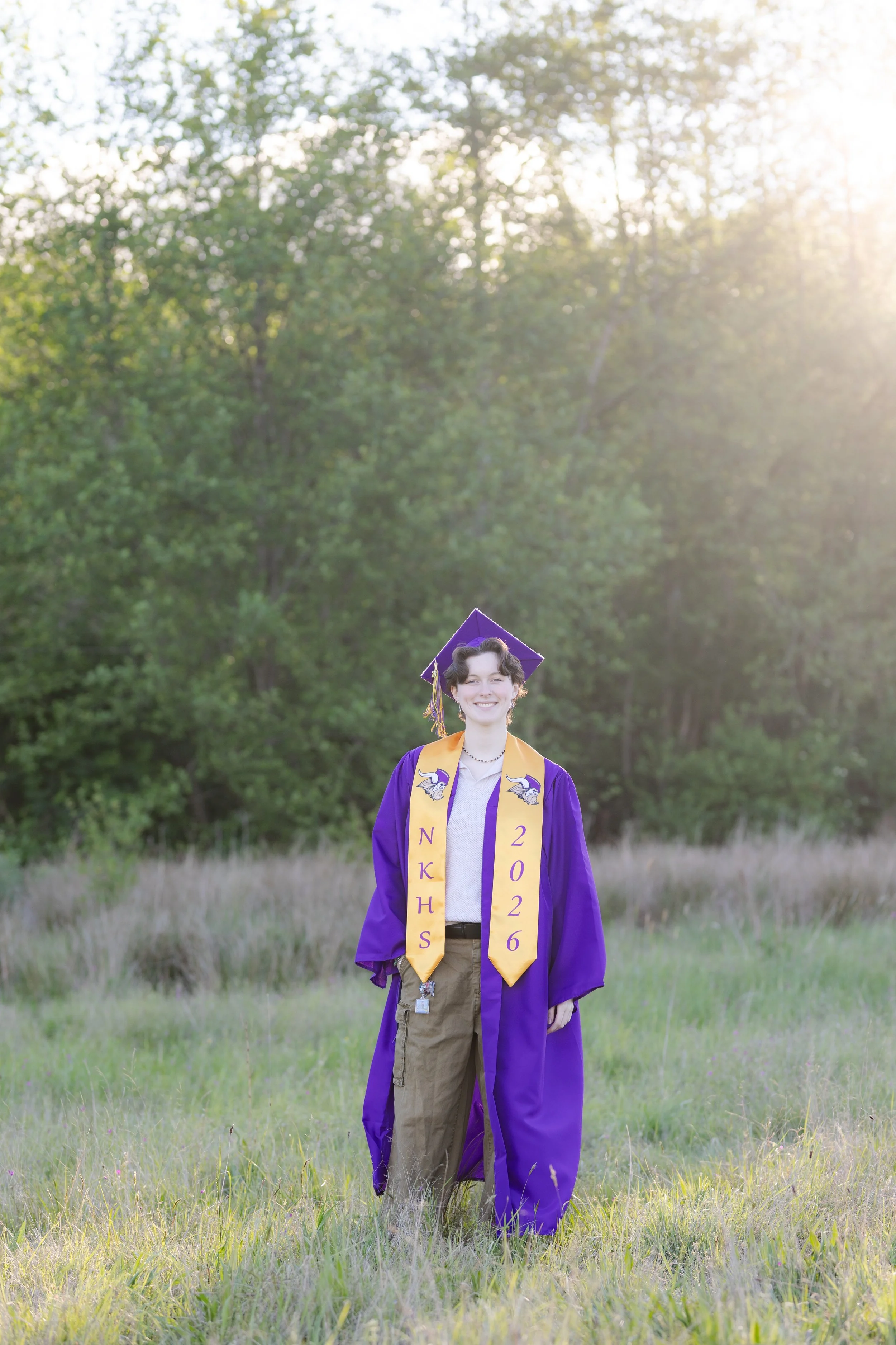 North Kitsap High School graduation picture in cap and gown in a grass field