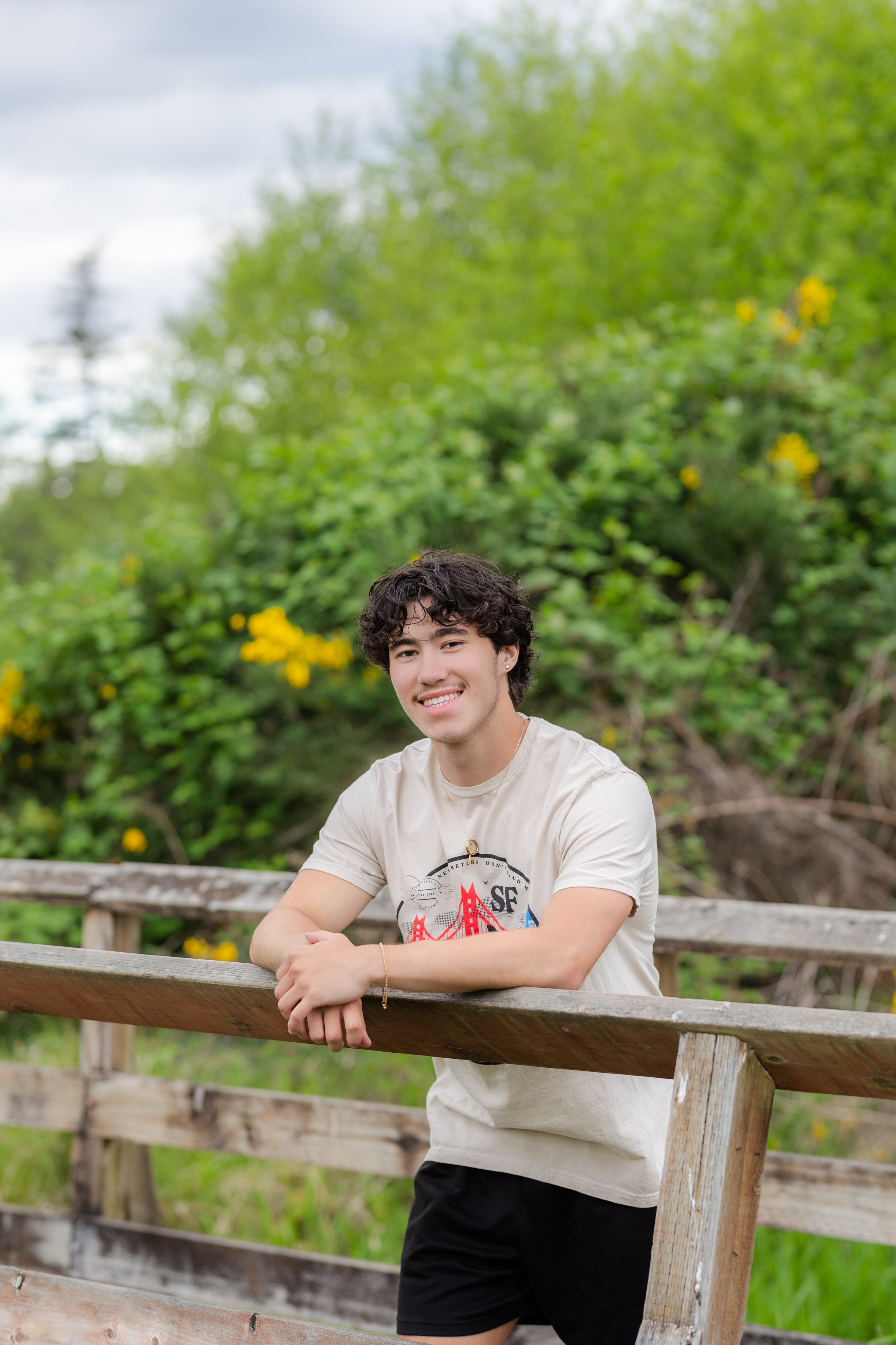 Senior photo of a boy leaning against a wooden bridge in Silverdale, WA