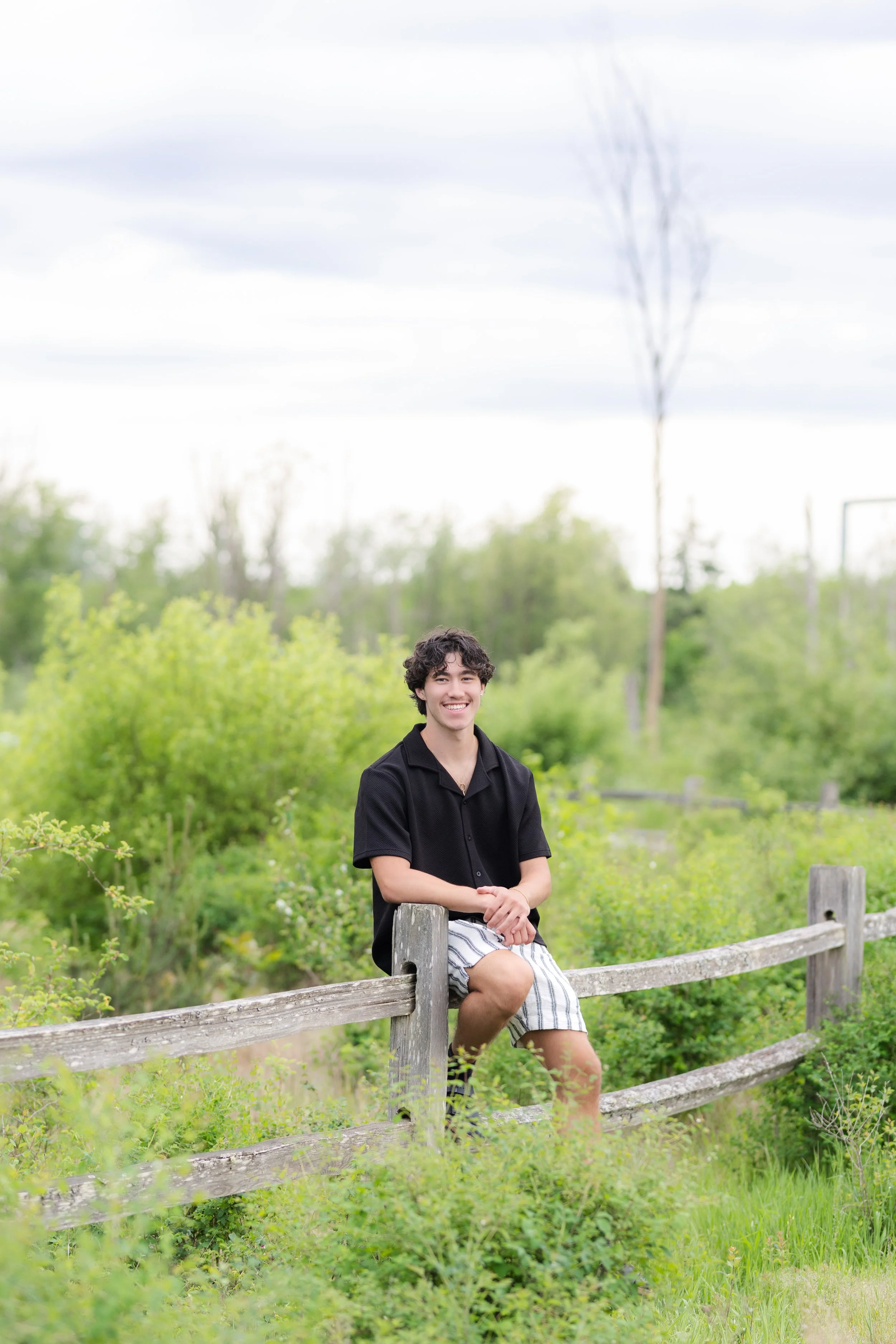 Silverdale senior picture of a boy sitting on a wooden fence