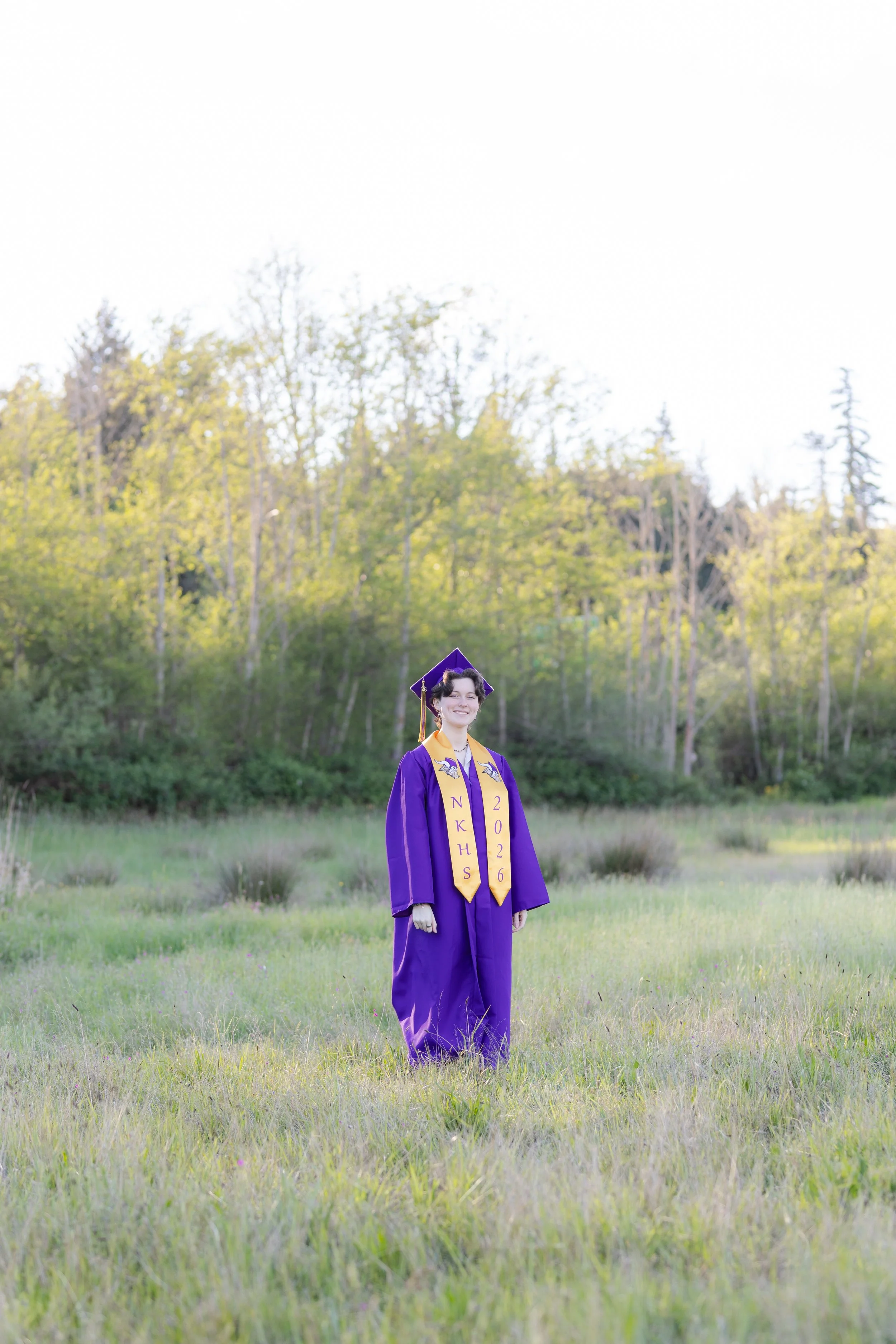 North Kitsap High School graduation picture in cap and gown in a grassy field