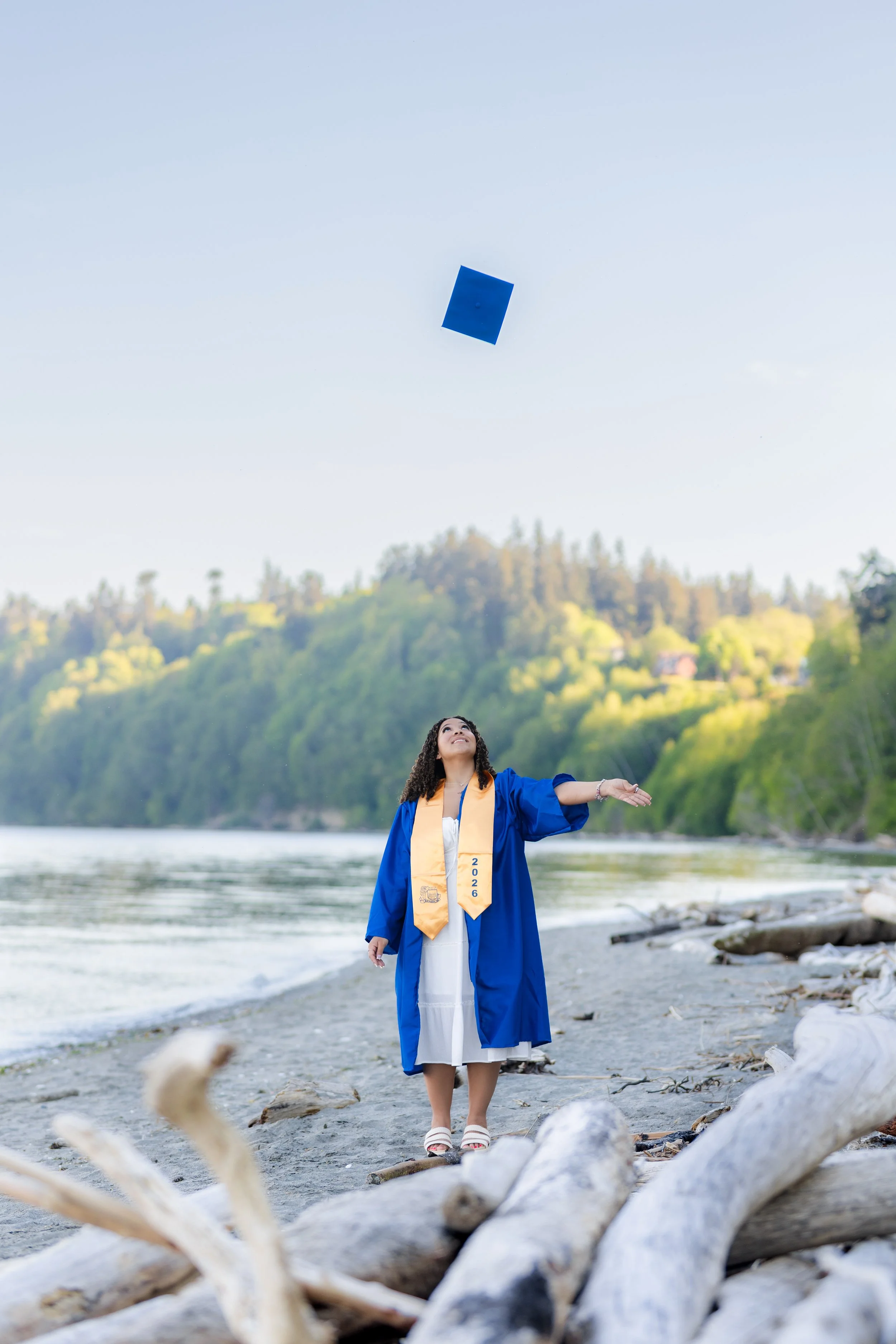 Graduation photo taken in Kitsap County of a senior doing a cap toss on the beach