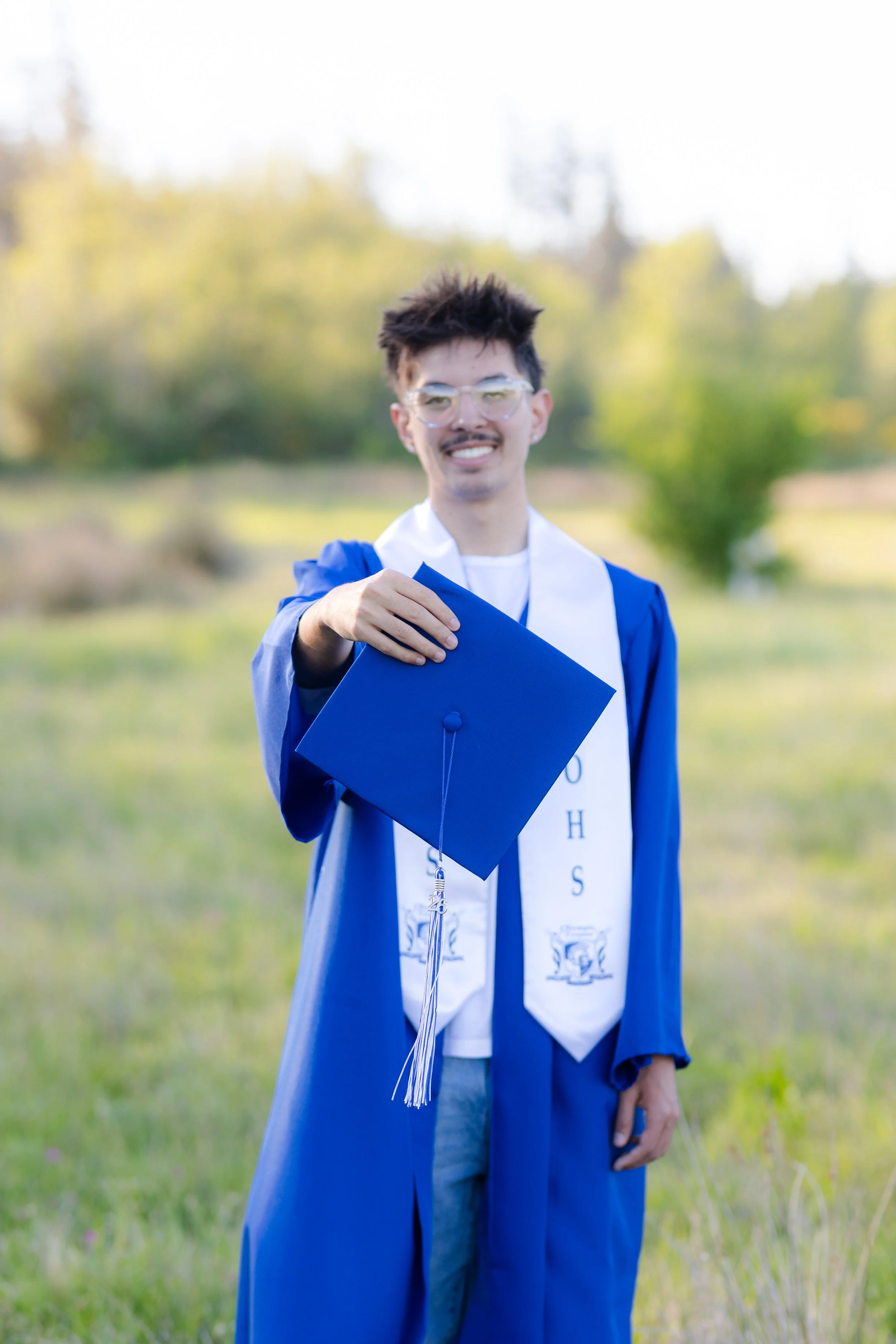 Olympic High School graduation photo taken in a grass field
