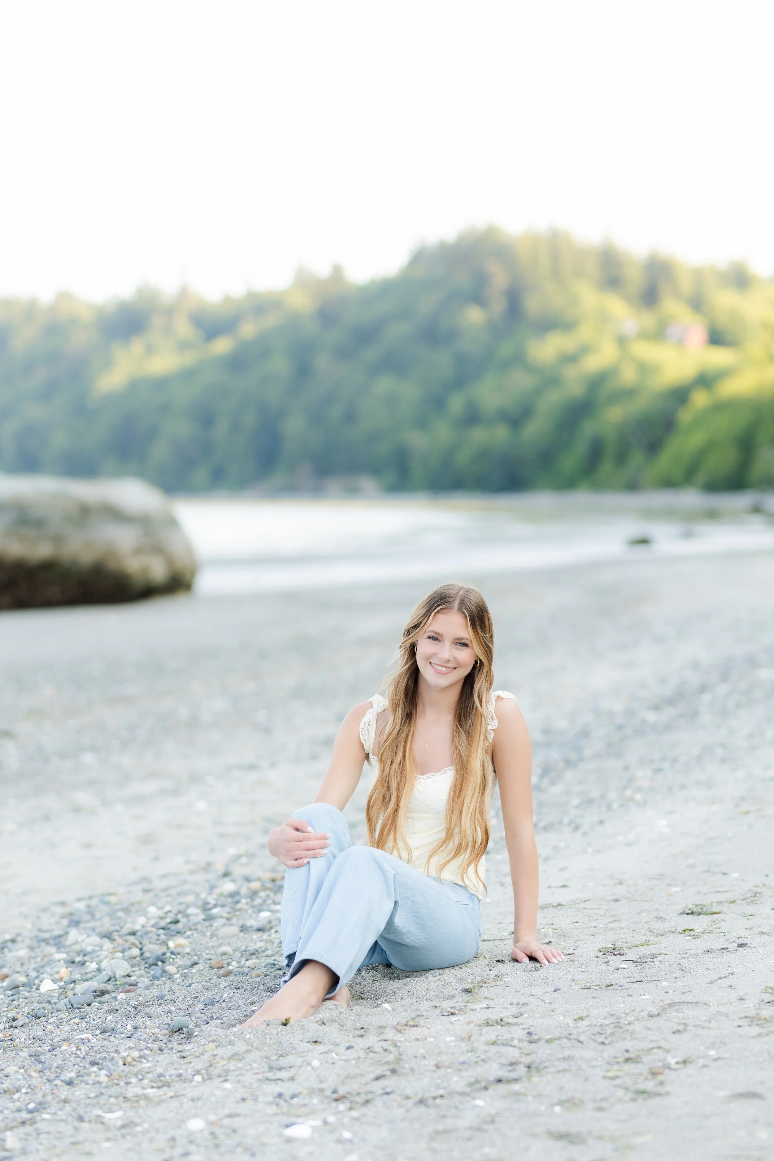 High school senior girl sitting on beach of Point No Point in Hansville, Washington for her senior portrait.