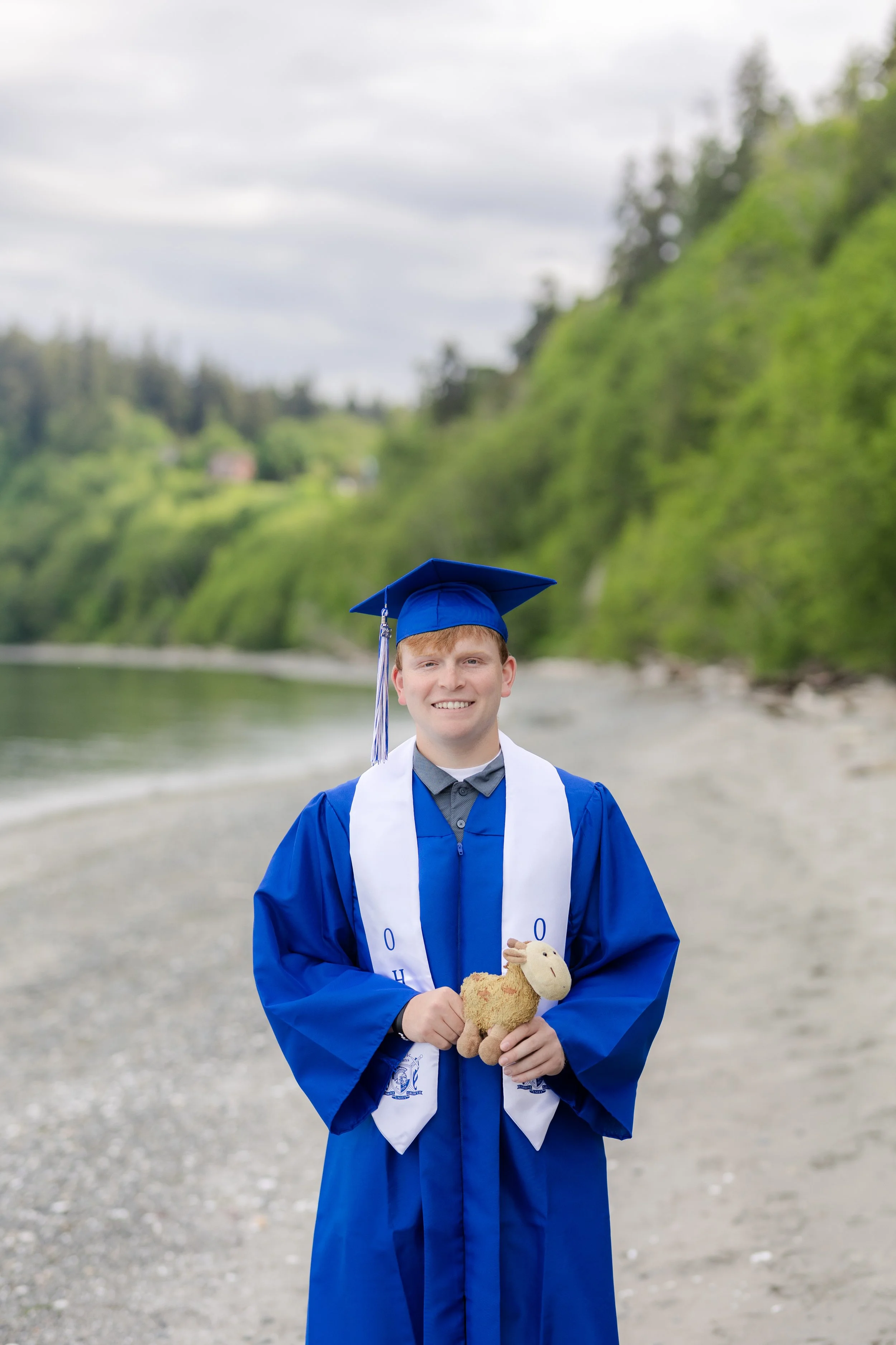 Cap and gown picture of a senior holding their childhood stuffed animal in Kitsap County, WA