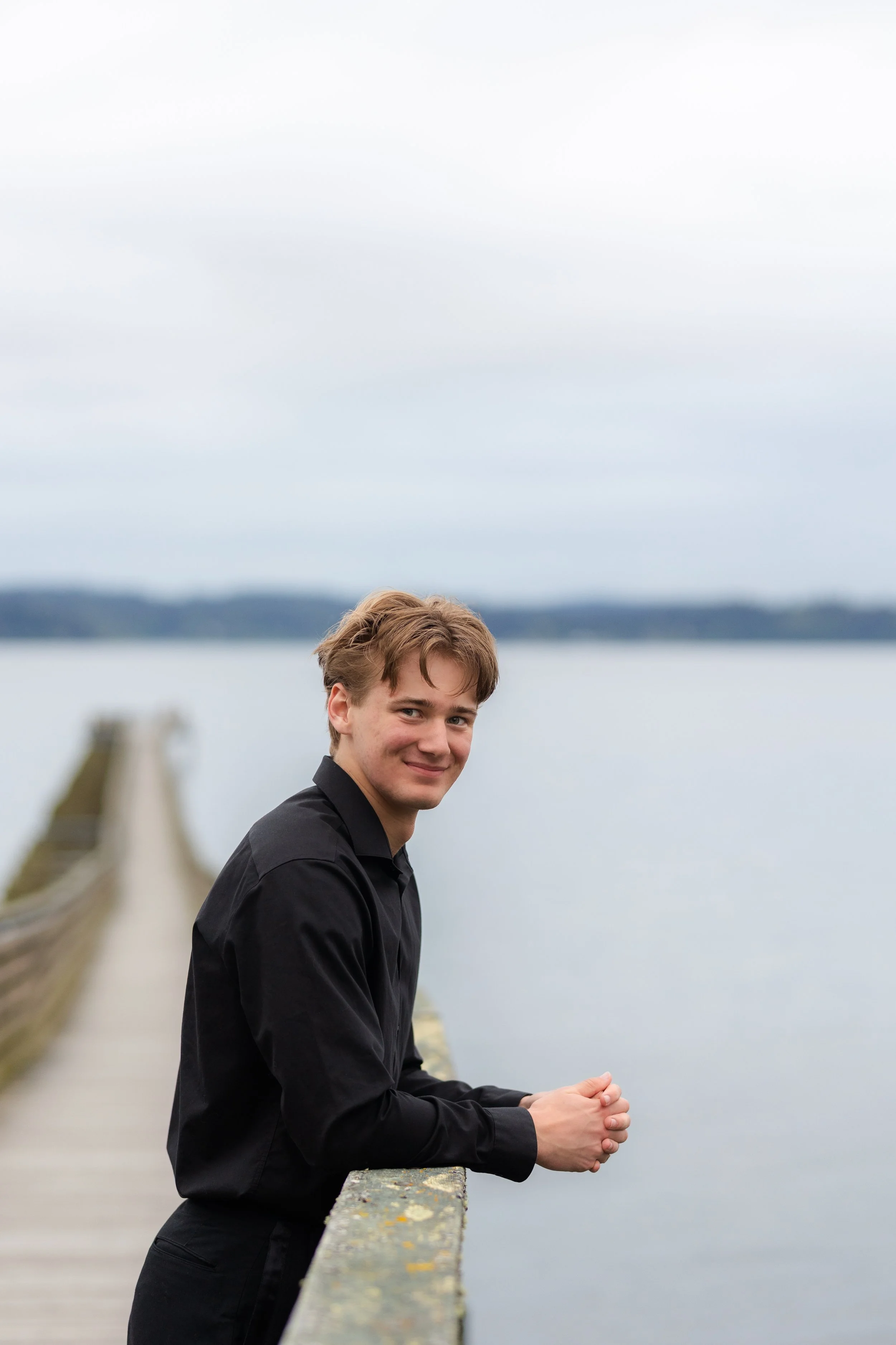Senior picture of a boy leaning against the railing of the Indianola Pier in WA