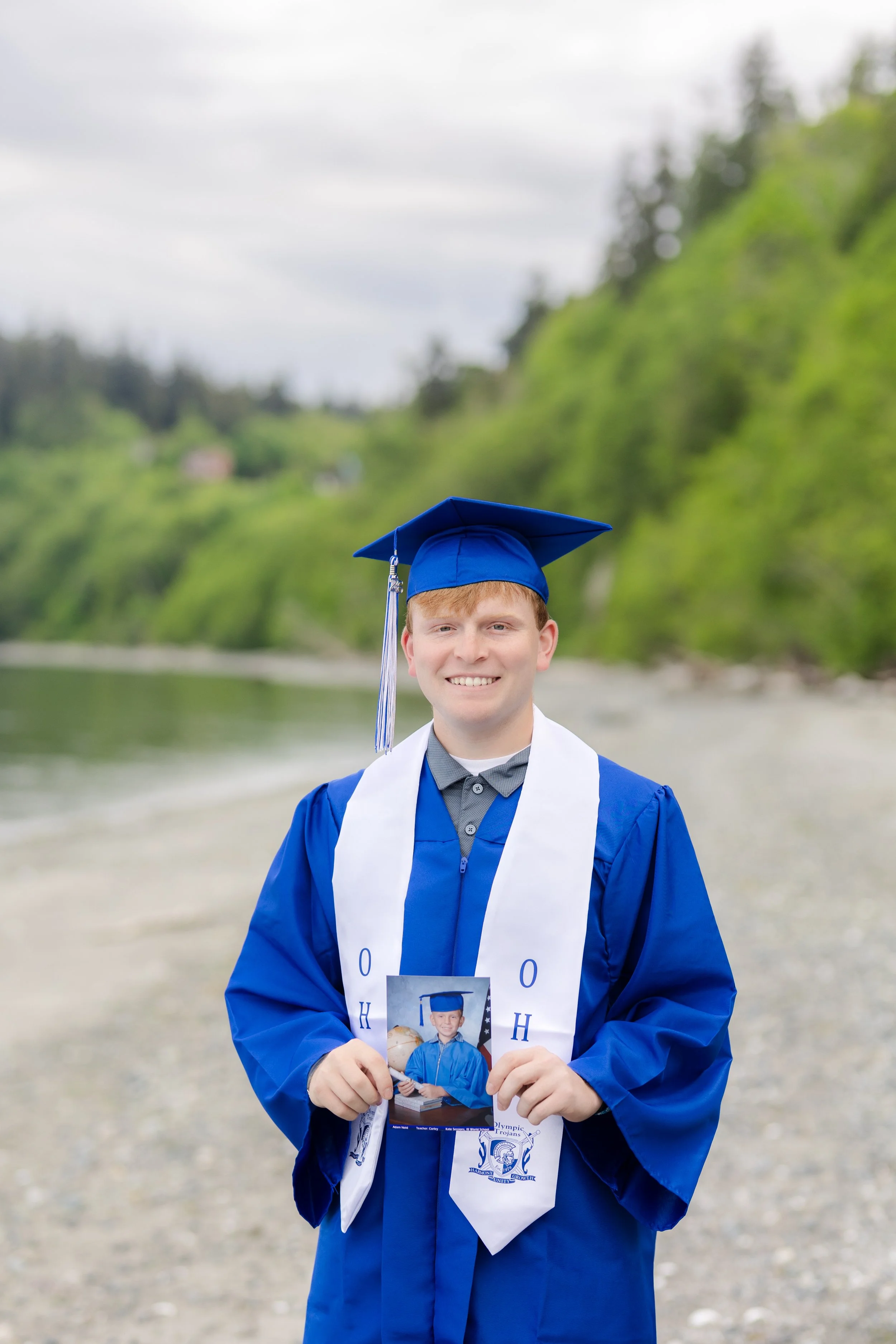 Cap and gown picture of a senior holding their kindergarten graduation picture in Kitsap County, WA