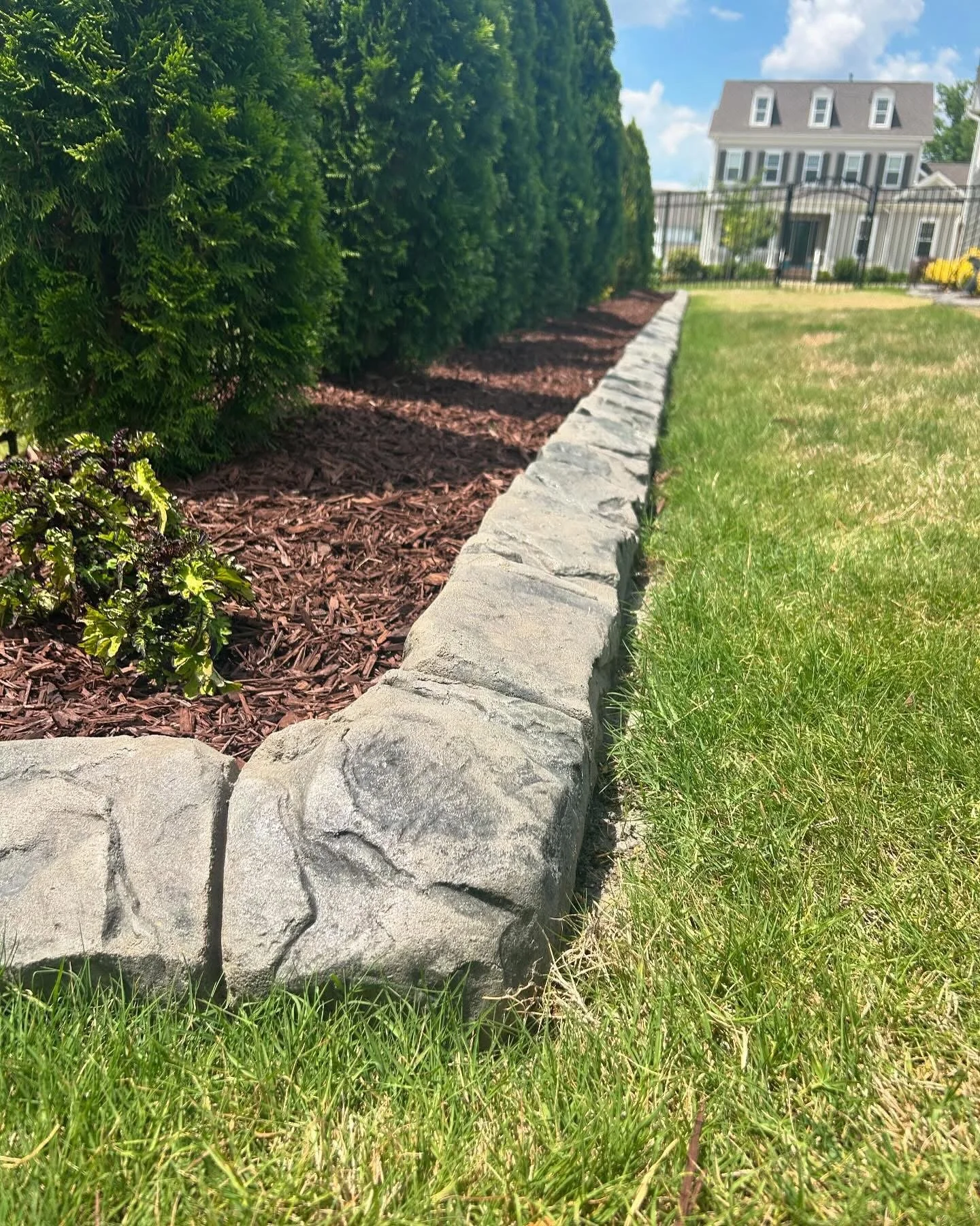 Close-up of squared corner of concrete curbing edge with a stone look around a garden bed
