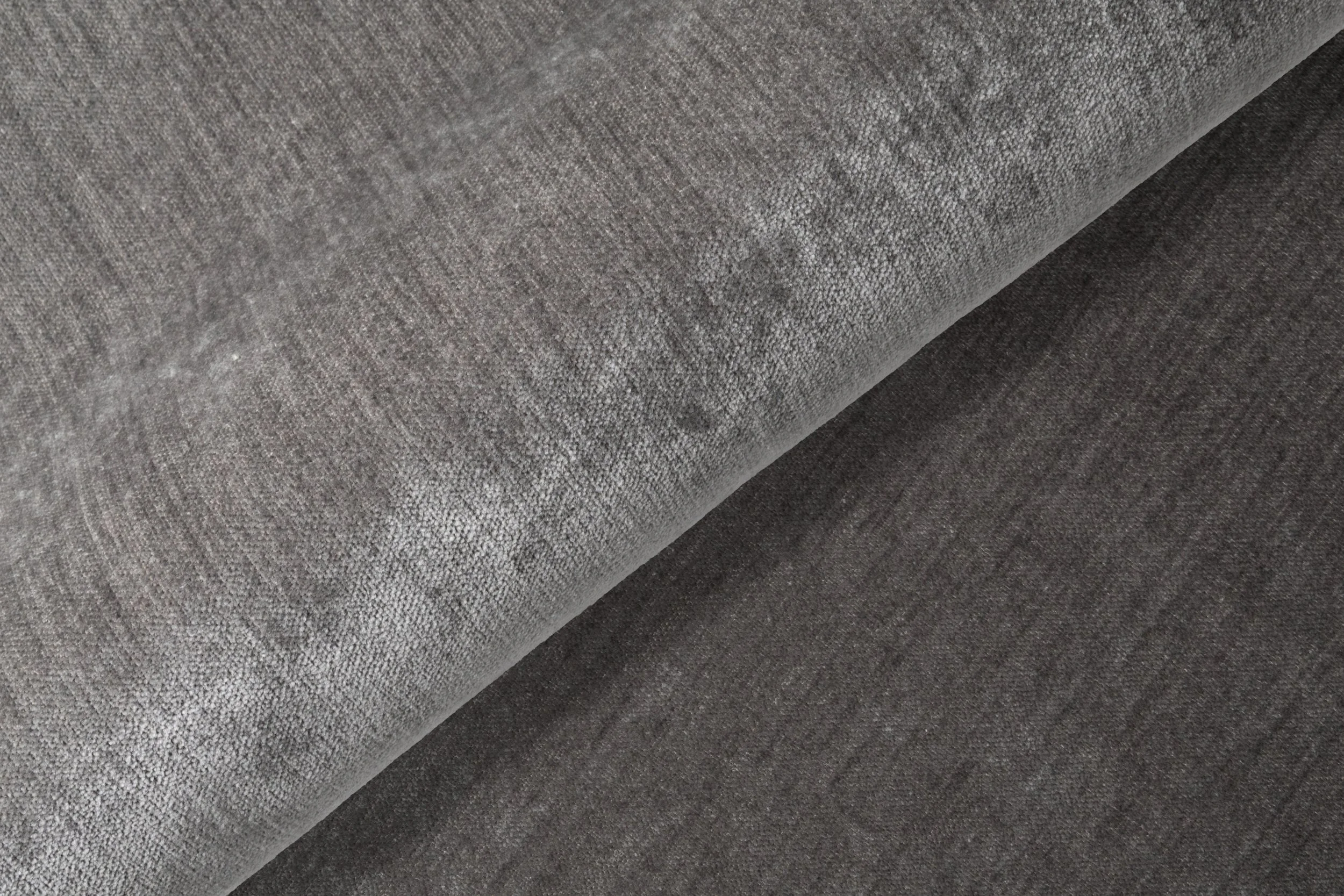 Två olika grå tyger, en med en ljusare och mer texturerad yta och en annan mörkare och slätare.