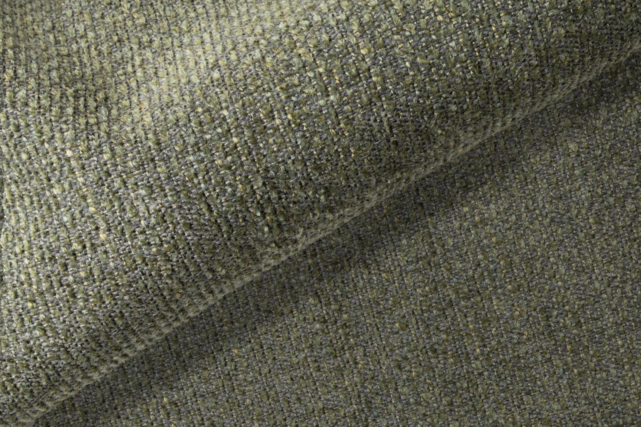 Detalj av en grönaktig, texturerad tygväv.