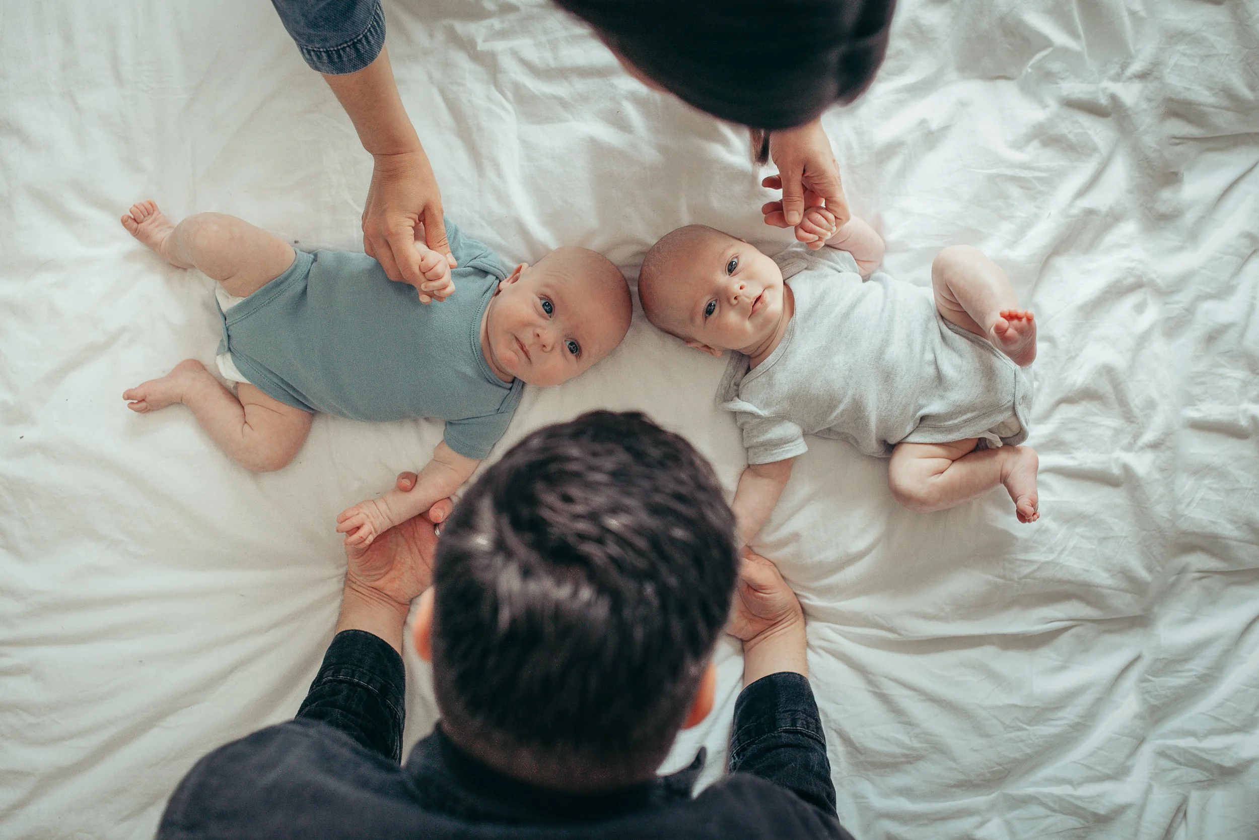 Image of two twin boys lying on a bed looking up towards the ceiling and camera.