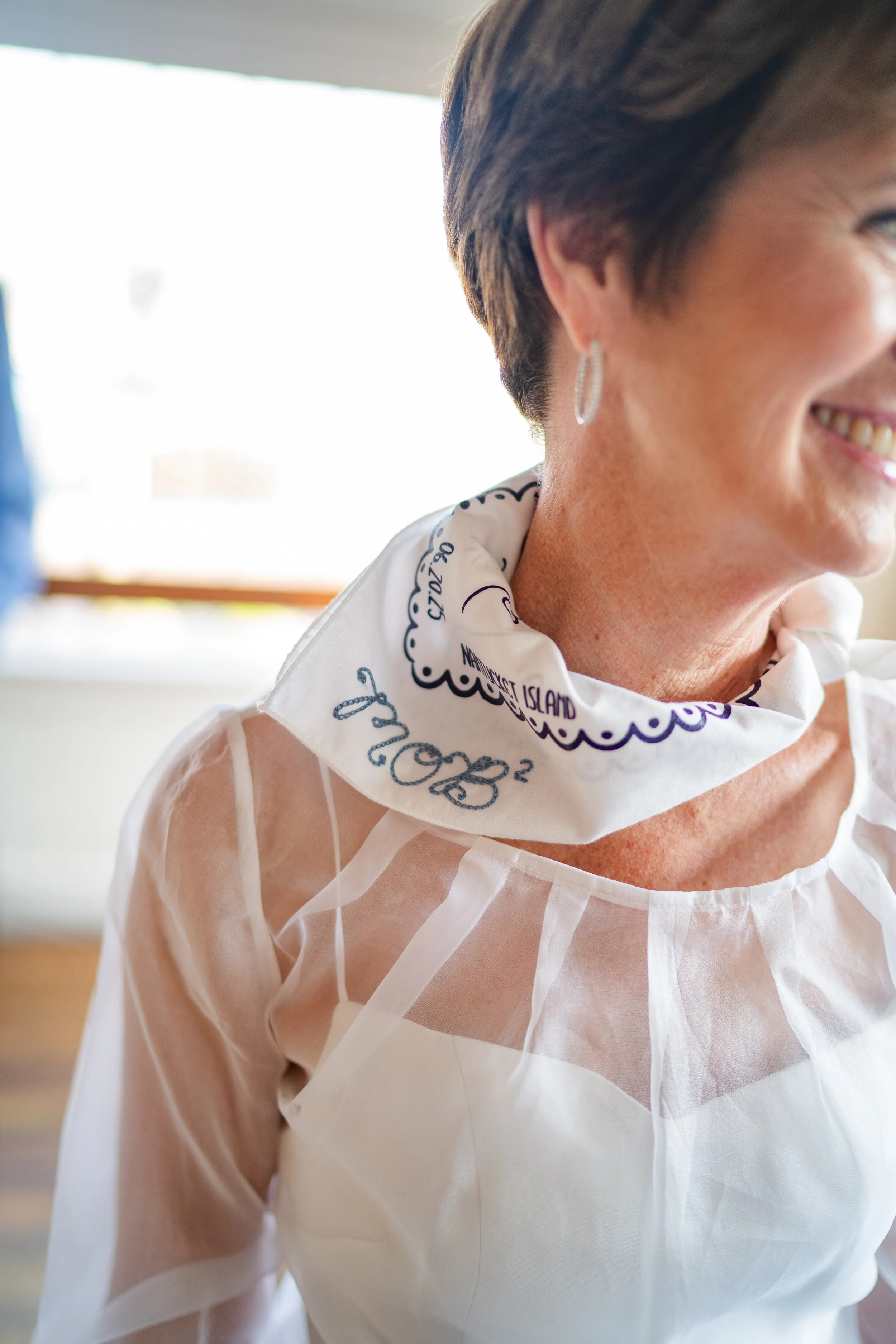 The Mother of the Bride (MOB) wearing a custom chainstitch bandana with the lettering MOB ^2 indicating she is the Mother of the Bride twice this year! The custom chainstitch bandana is white with marine blue stitching.