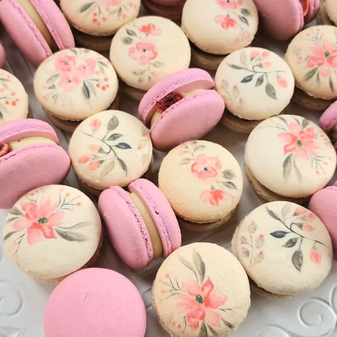 Assorted pink and white specialty design macarons with floral designs and filling.