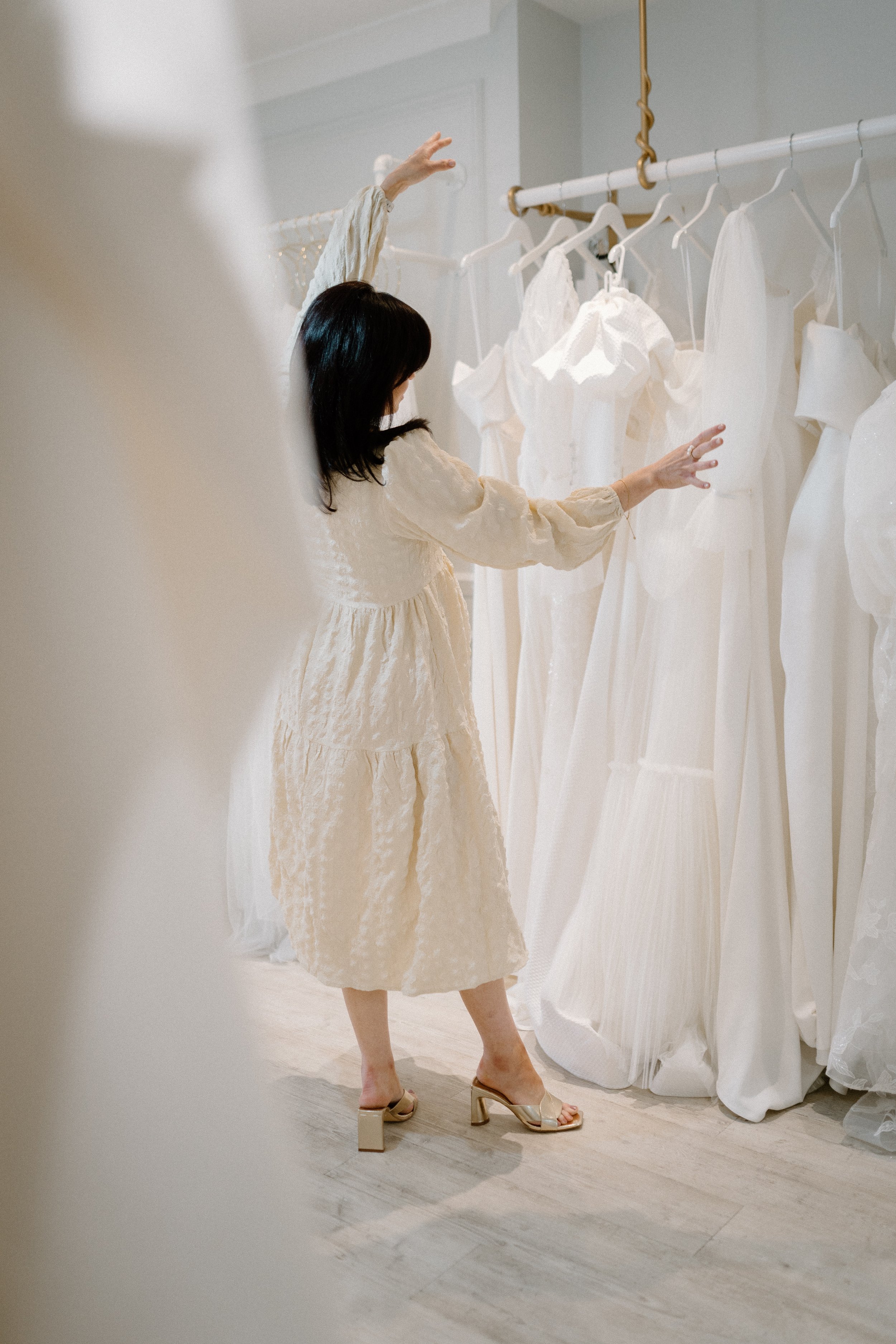 A woman trying on a beige dress in a bridal boutique.
