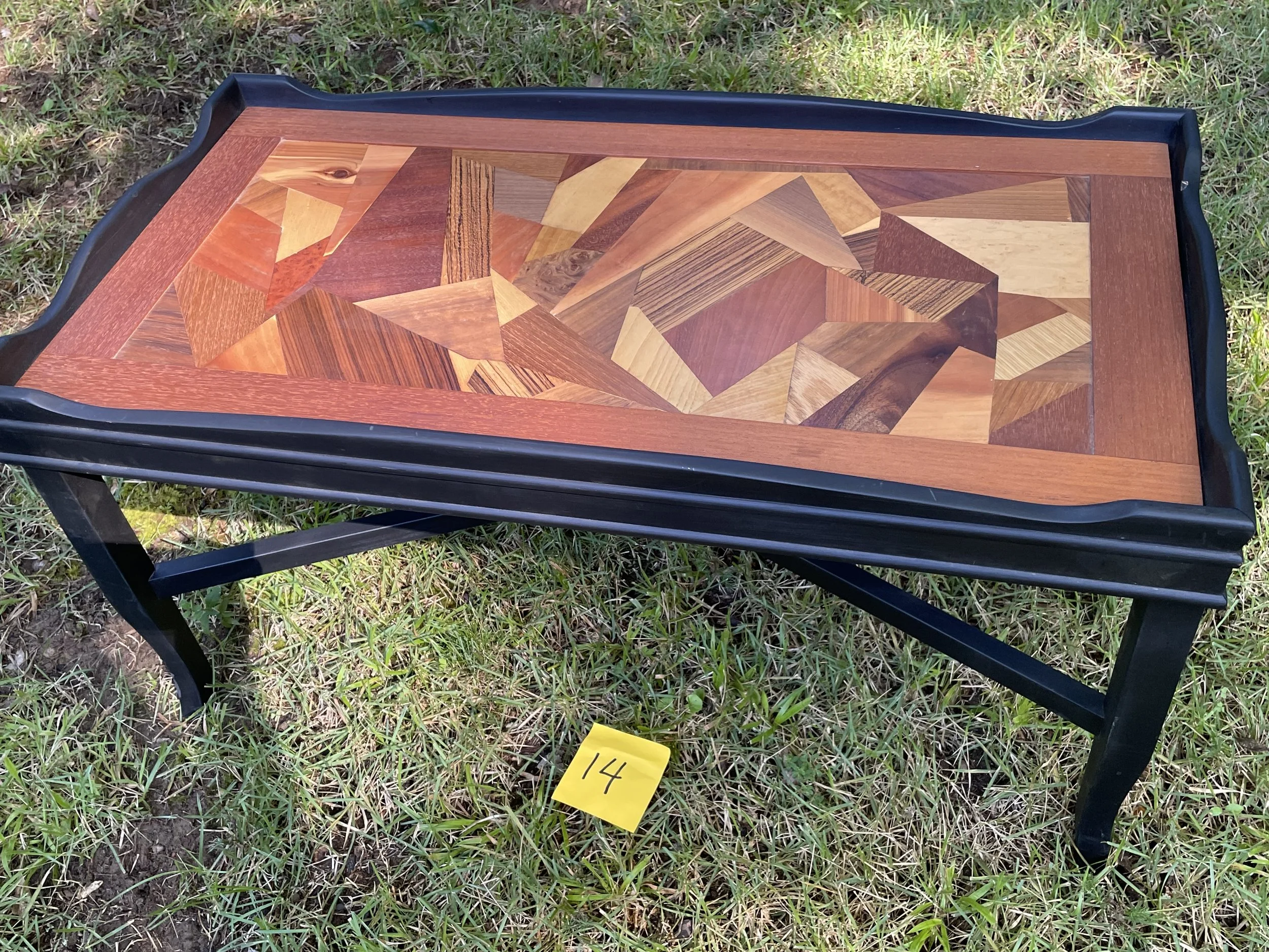Wooden tray table with geometric inlaid design on grass