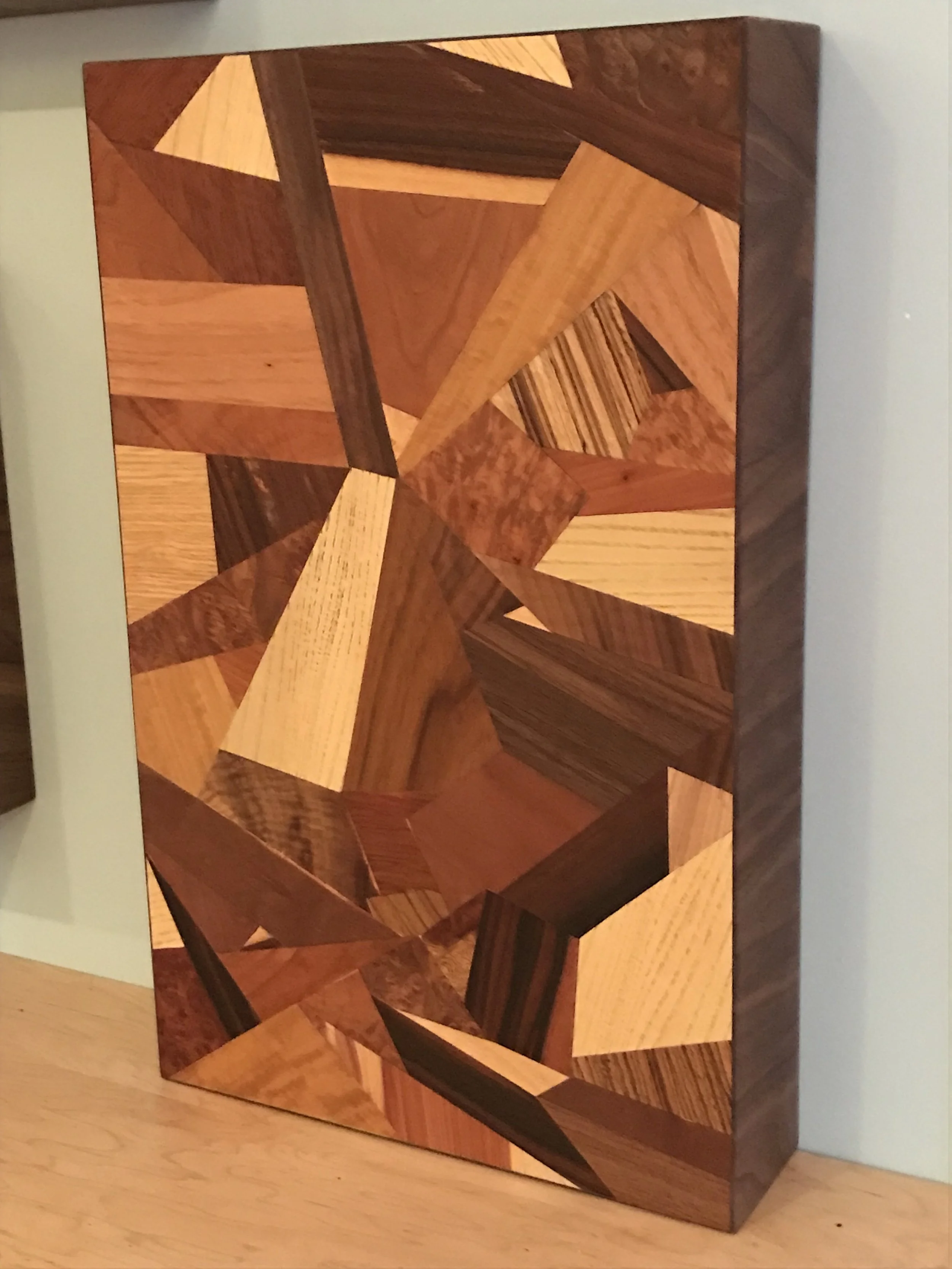 Geometric wooden mosaic art piece with various shades of brown on a wooden surface.