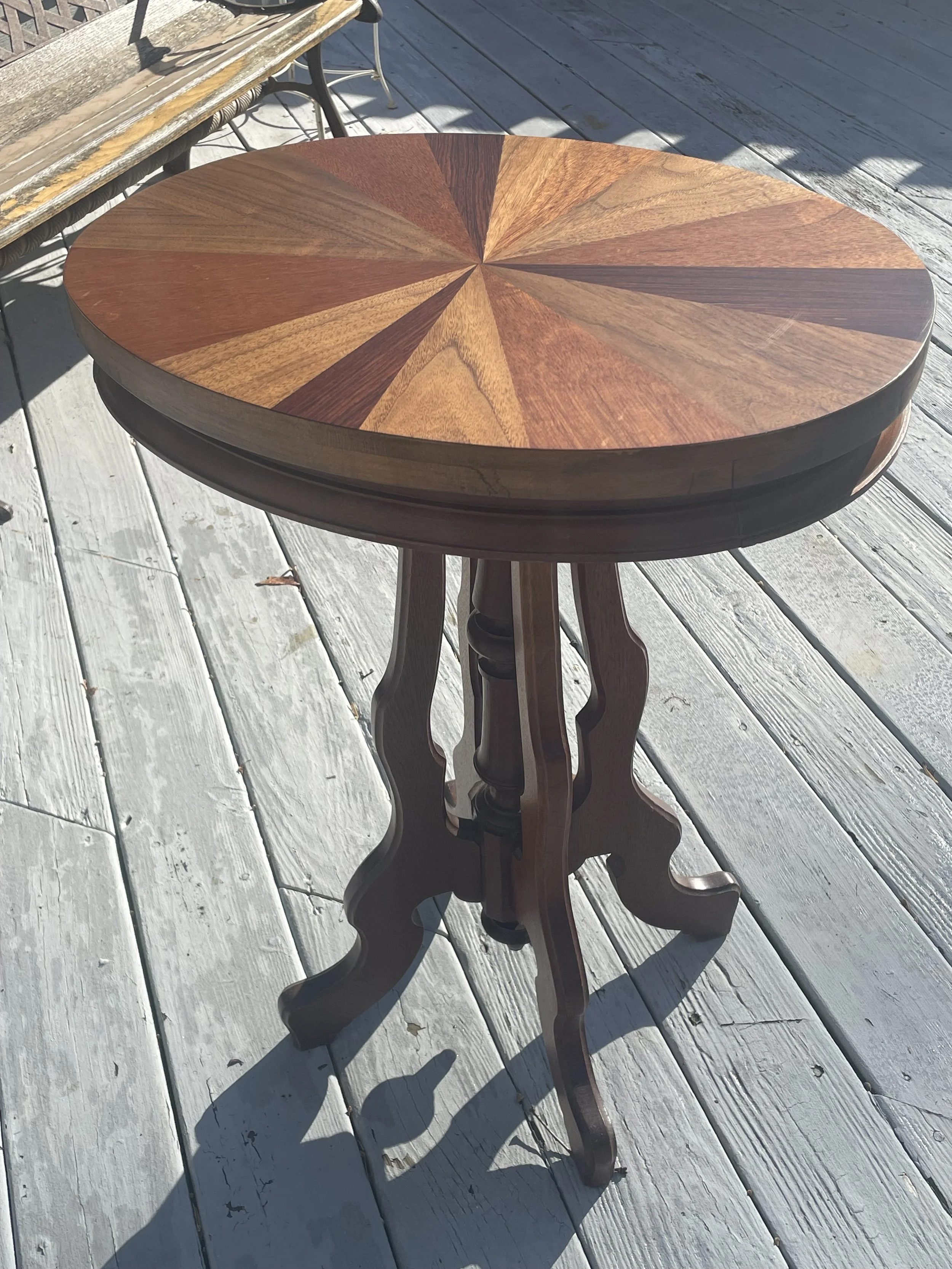 Round wooden table with sunburst pattern on a deck