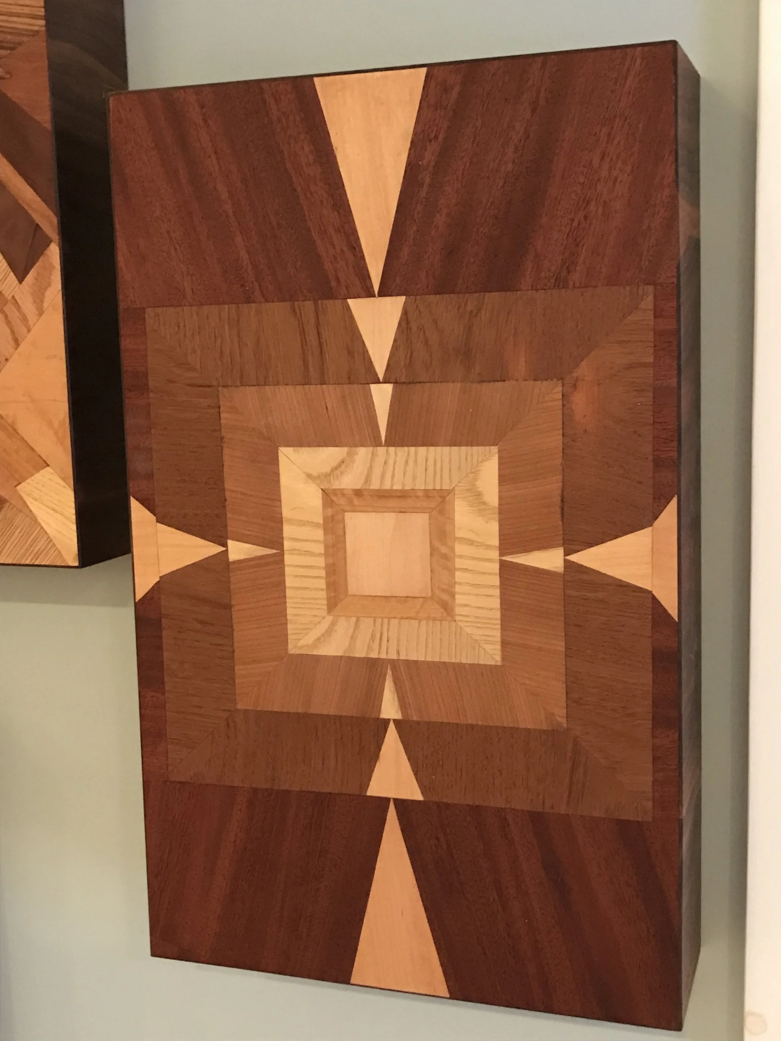 geometric wood art piece with symmetrical square and triangular patterns