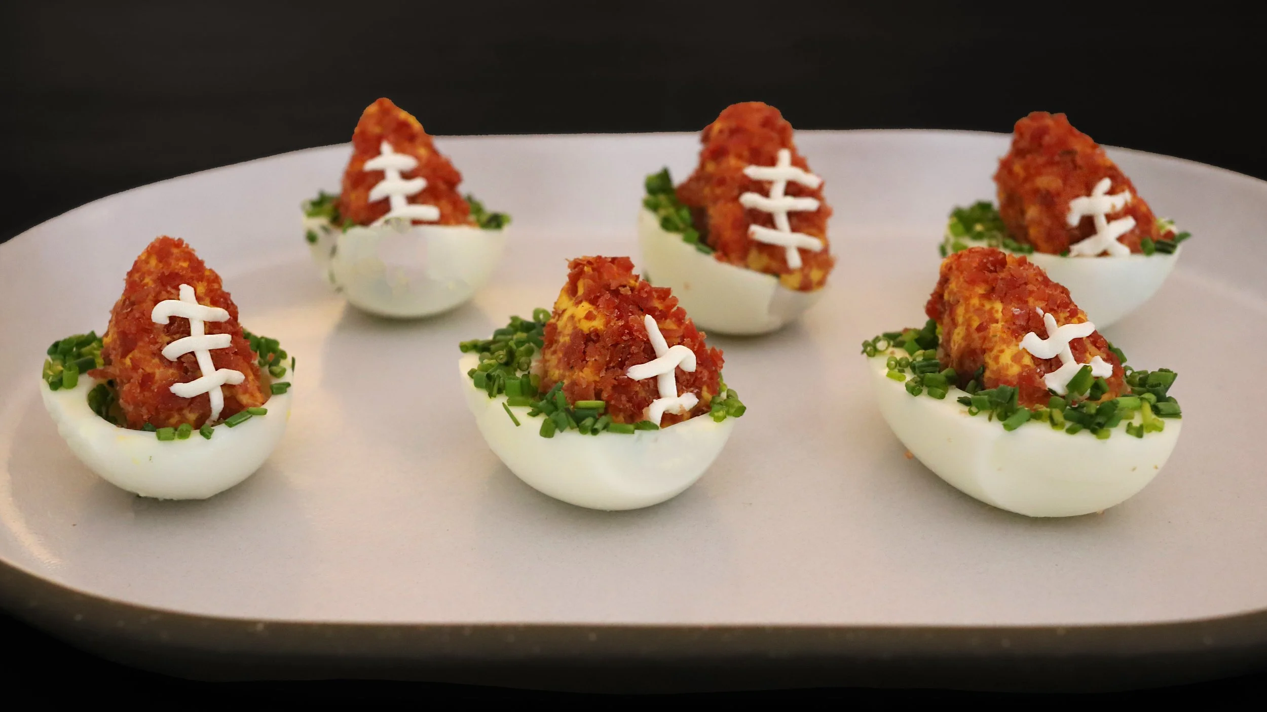 FOOTBALL-SHAPED DEVILED EGGS WITH TURKEY BACON CRUST & CHIVE “FIELD”