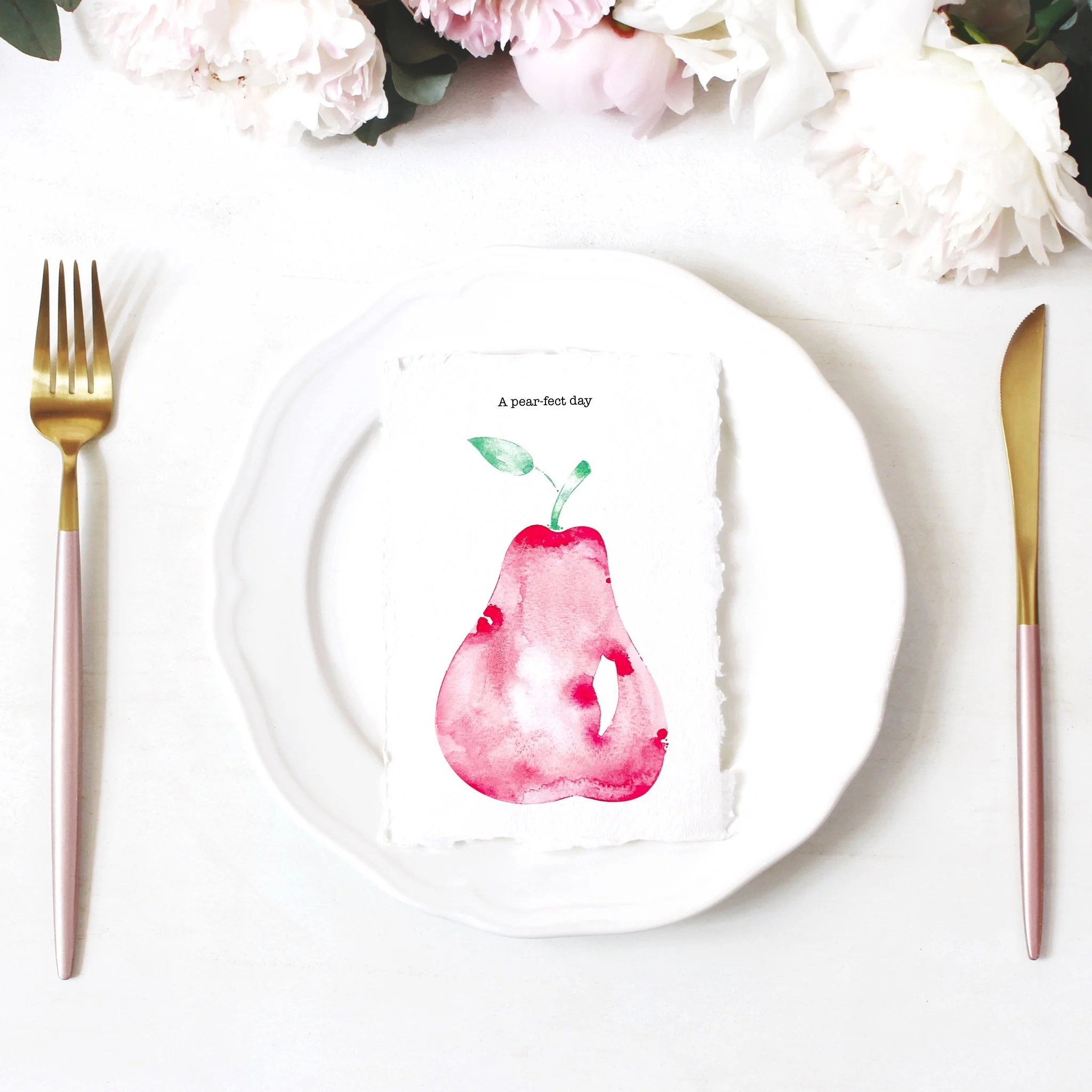 A white plate with a green leaf illustration and the text 'A pear-fect day' on it, surrounded by pink and white flowers, a gold fork on the left, and a gold knife on the right, all set on a white background.